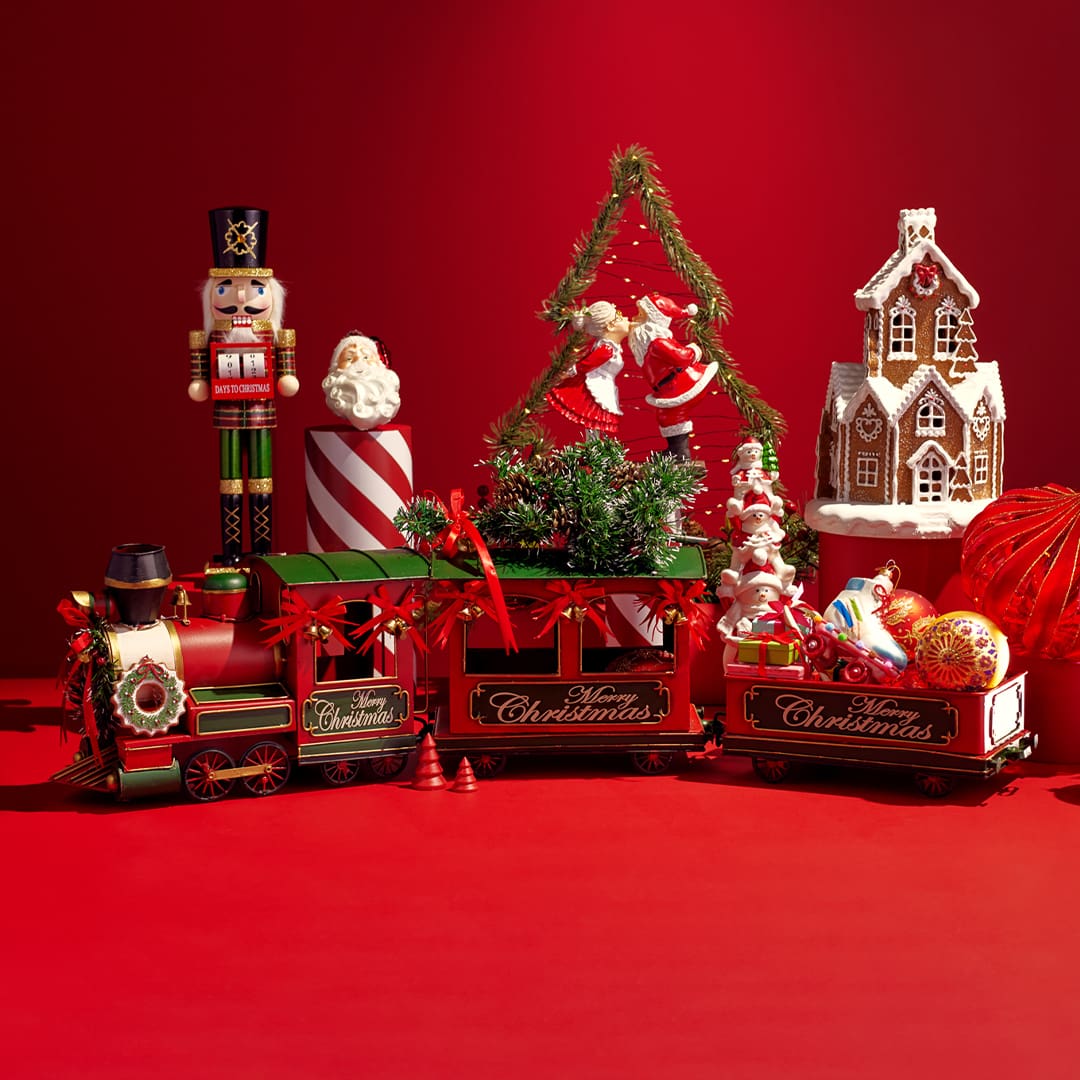 Christmas-themed decorations, including a toy train, nutcracker, gingerbread house, and festive ornaments on a red background.