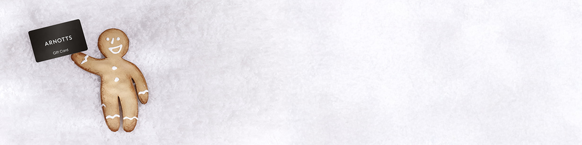 A gingerbread cookie holding an 'Arnotts Gift Card' on a snowy background.