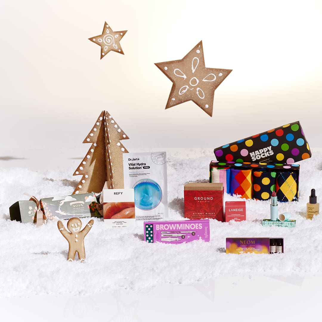Assorted gift items on fake snow with a gingerbread figure, cardboard trees, and star decorations.