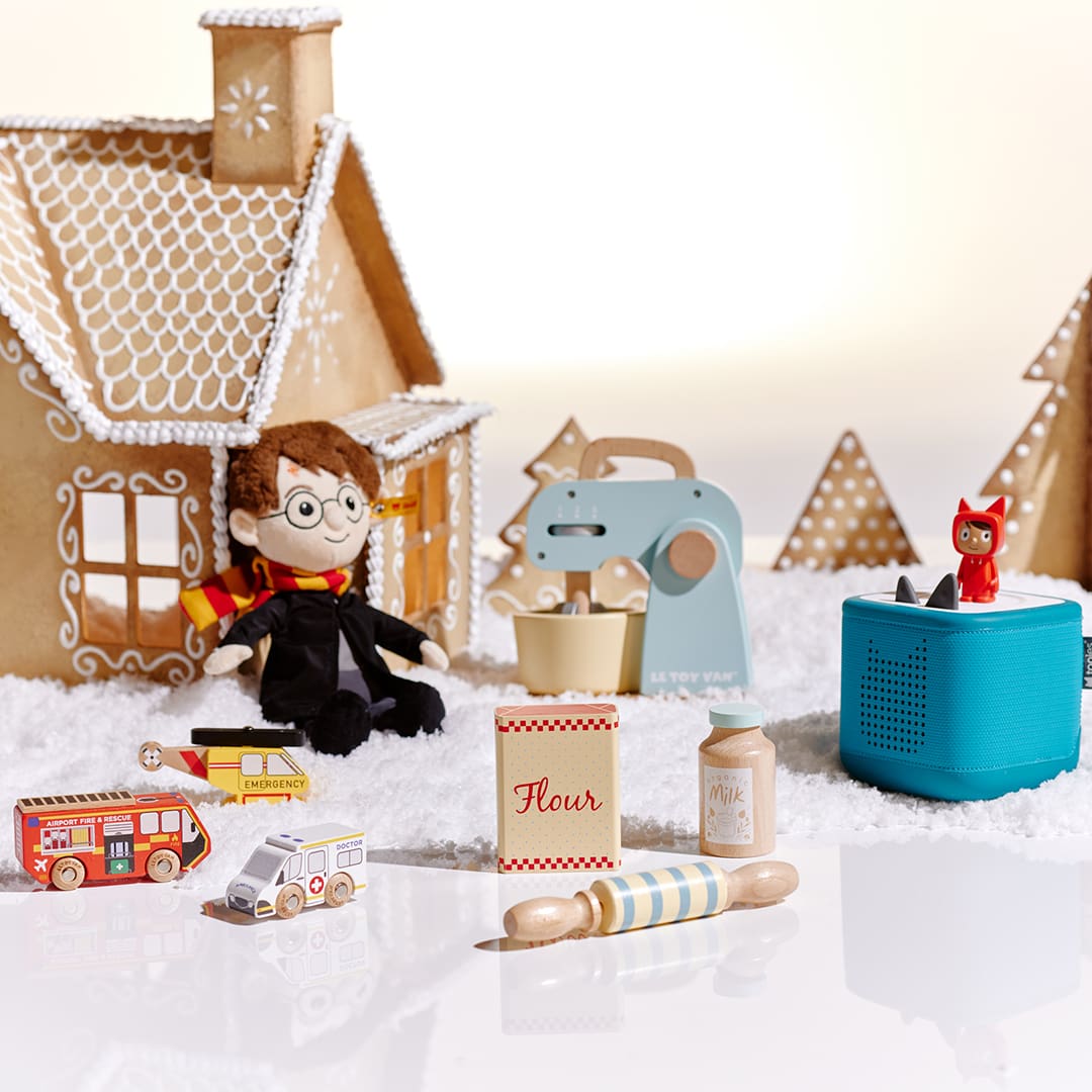 Gingerbread houses with toys, including a doll in glasses, mixer, blocks, and a small figurine on a blue box.