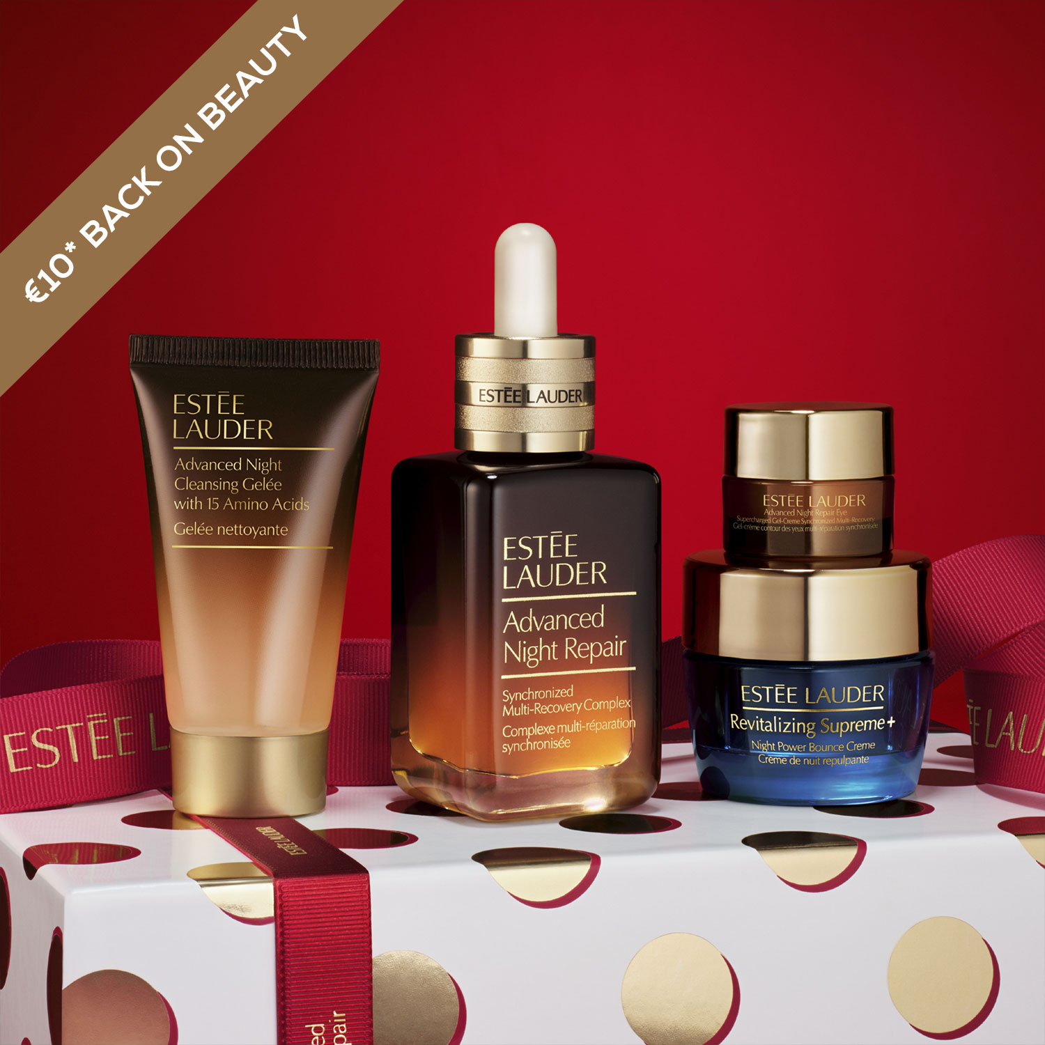 Estee Lauder skincare products displayed on a polka dot gift box with a red background.