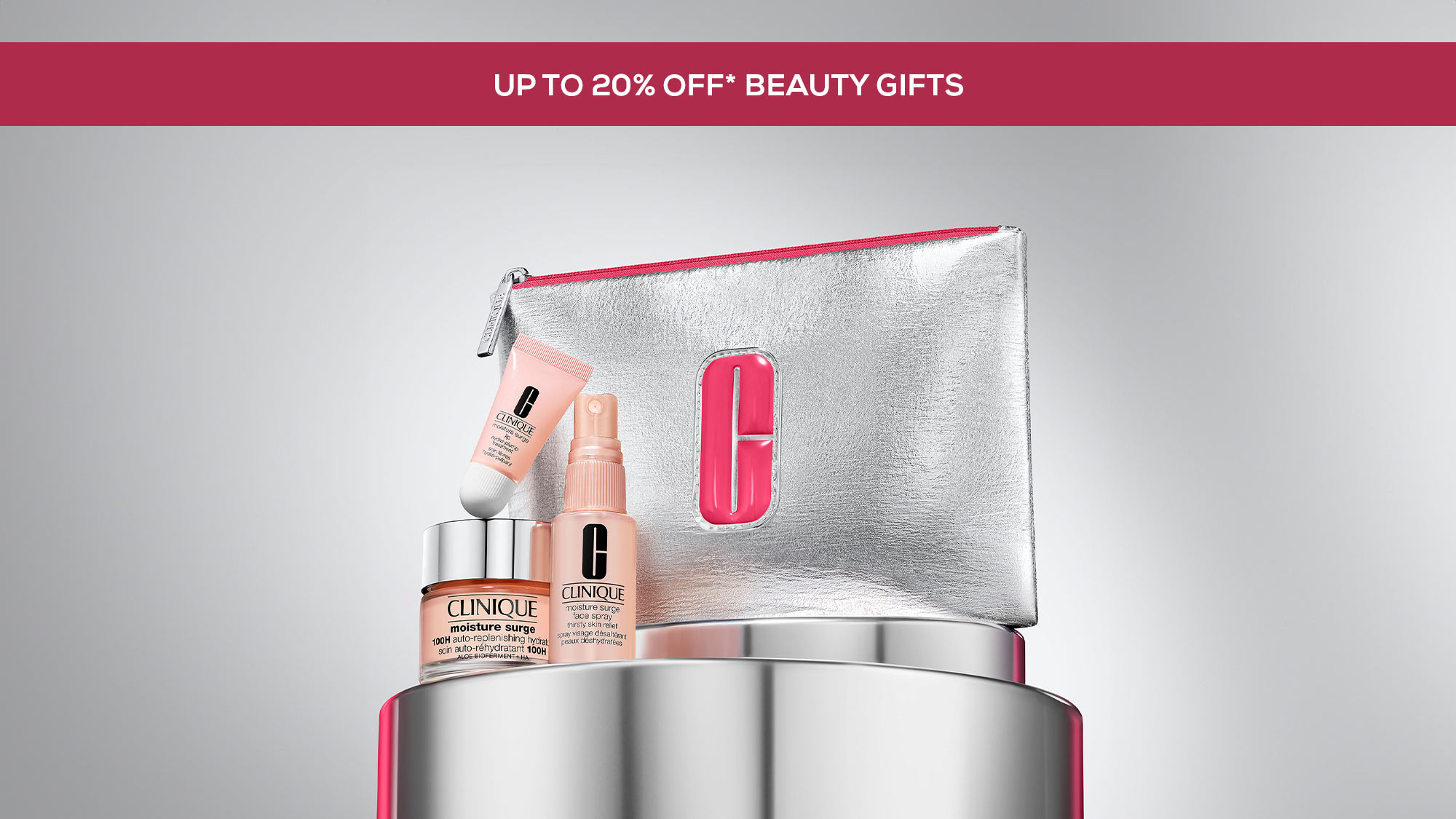 Cosmetic set with skincare products and a silver pouch with pink lining, branded 'Clinique,' displayed on a reflective surface.