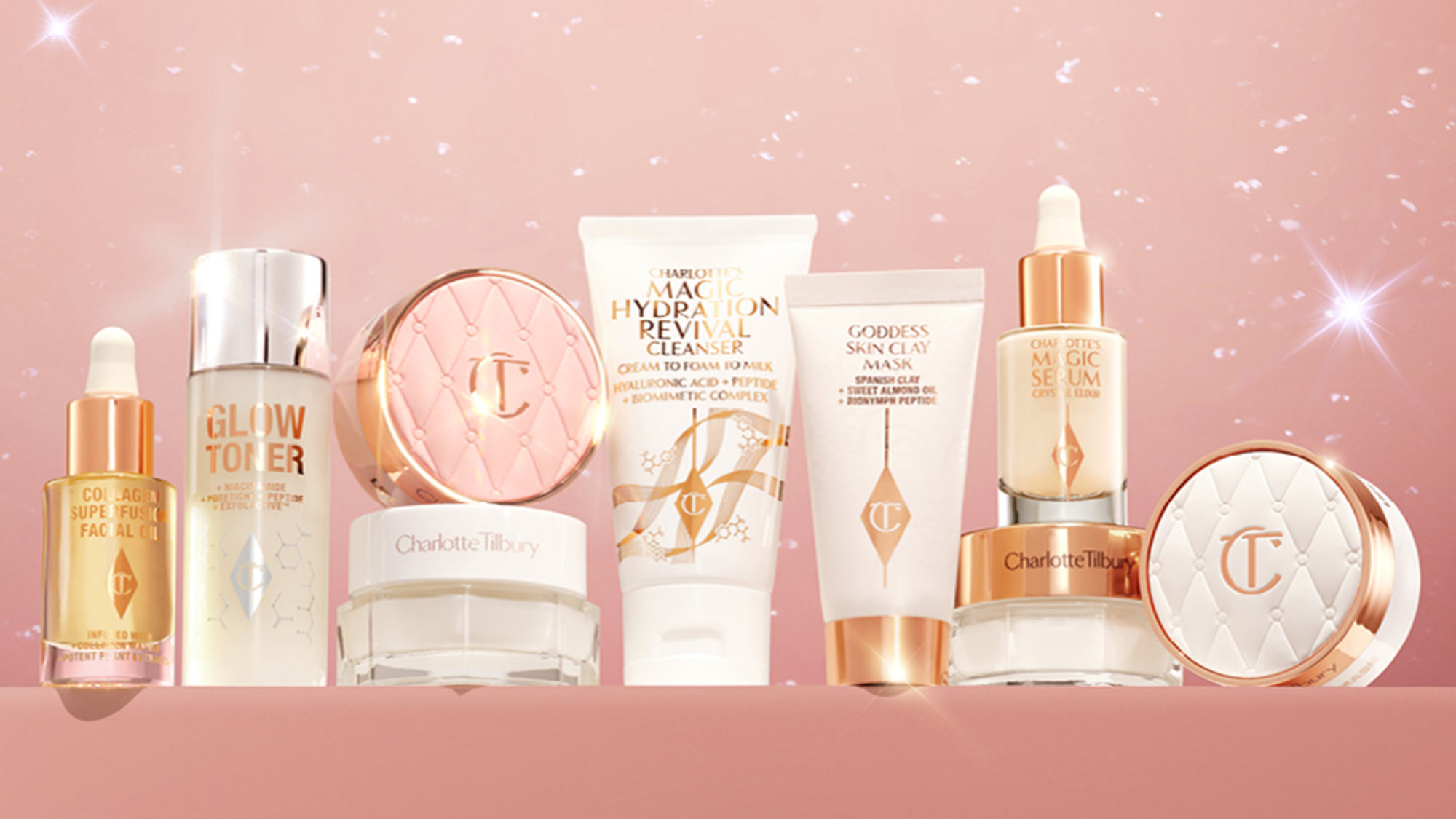 A collection of skincare and cosmetic products displayed against a sparkling pink background.