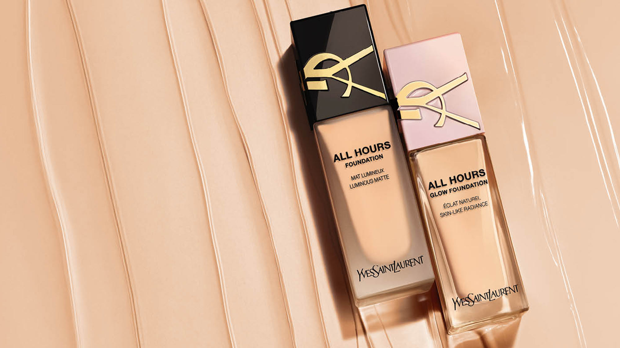 Two bottles of Yves Saint Laurent All Hours Foundation on a textured beige surface.