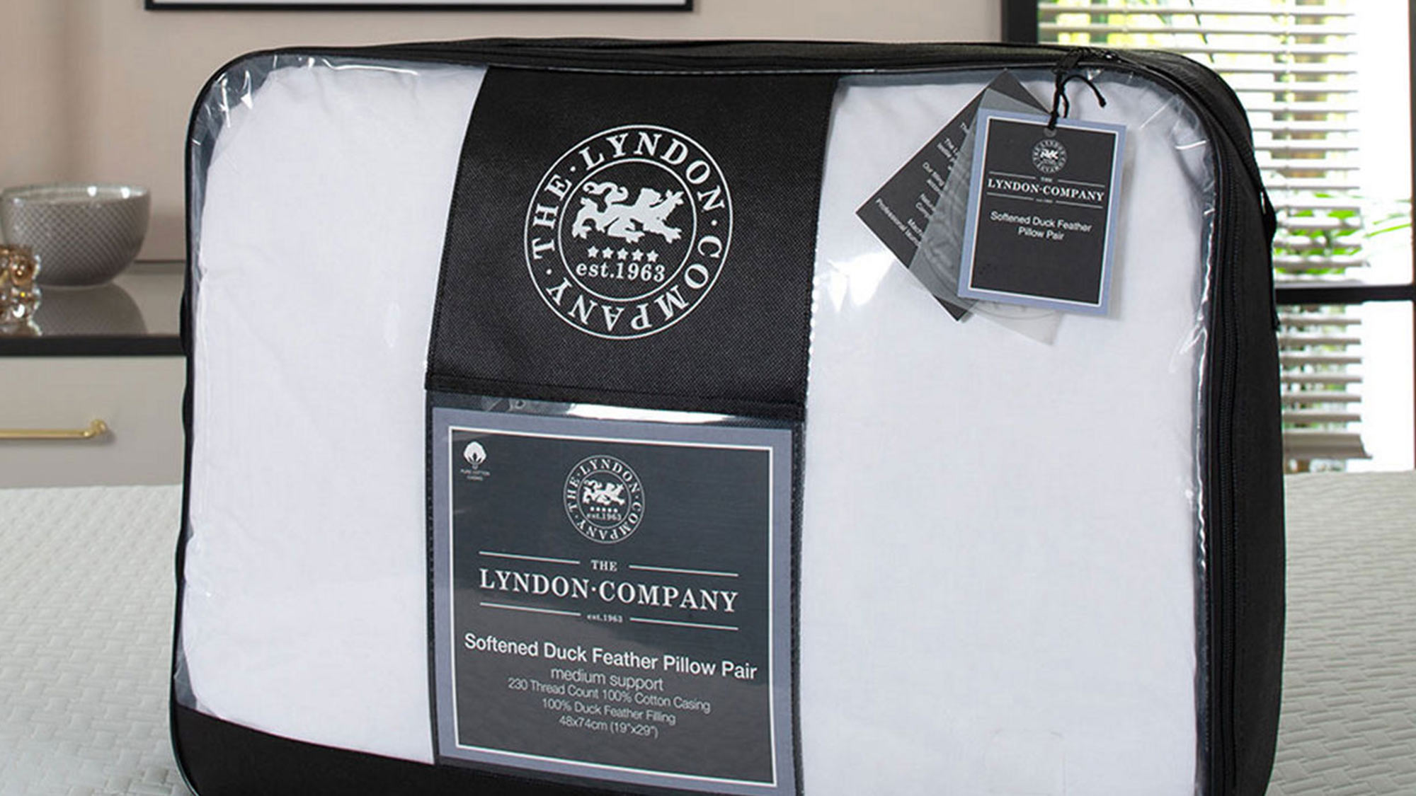 Packaged pair of white duck feather pillows from The Lyndon Company on a bed.