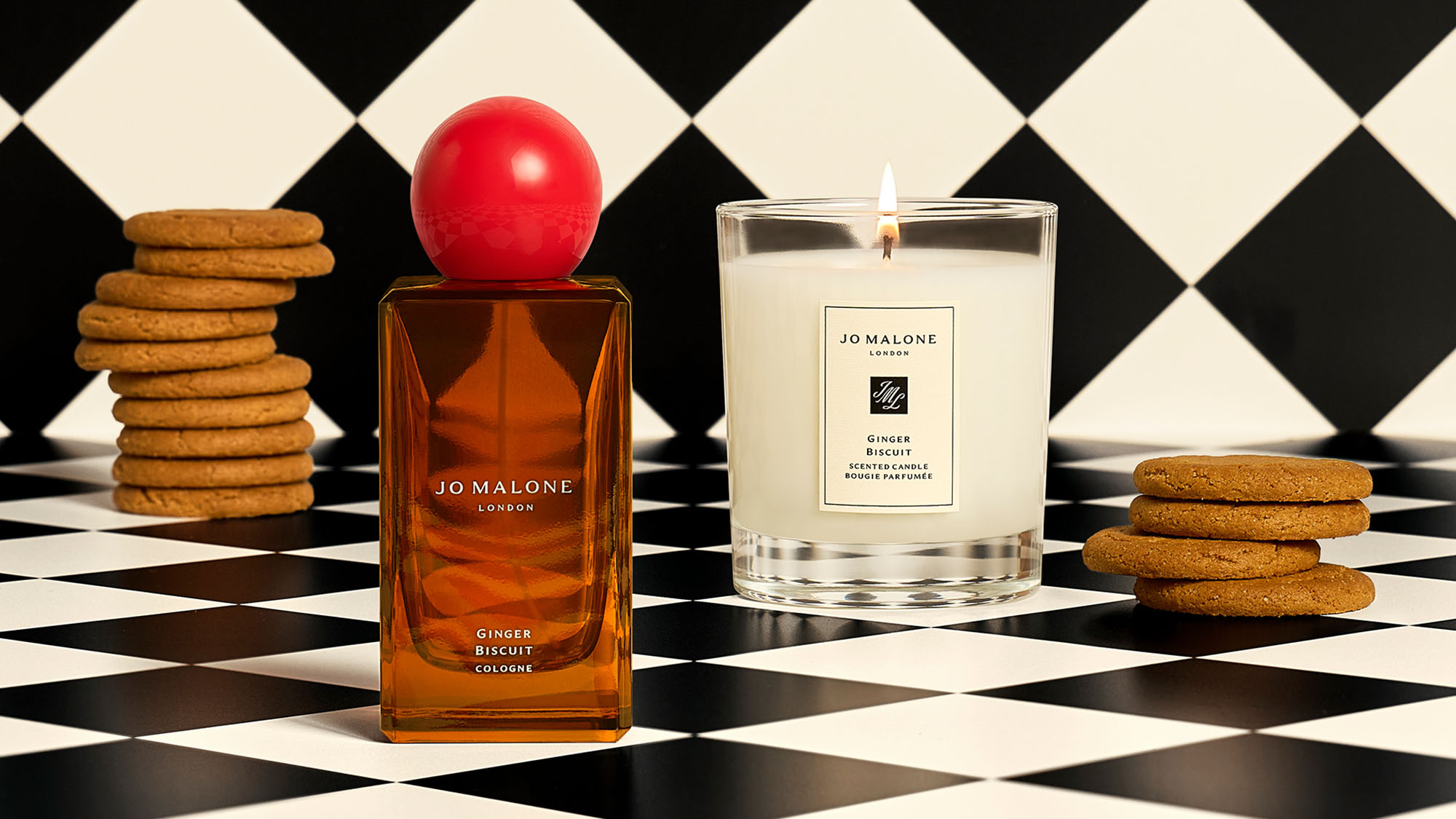 Perfume and candle on a black-and-white checkered surface, surrounded by cookie stacks.