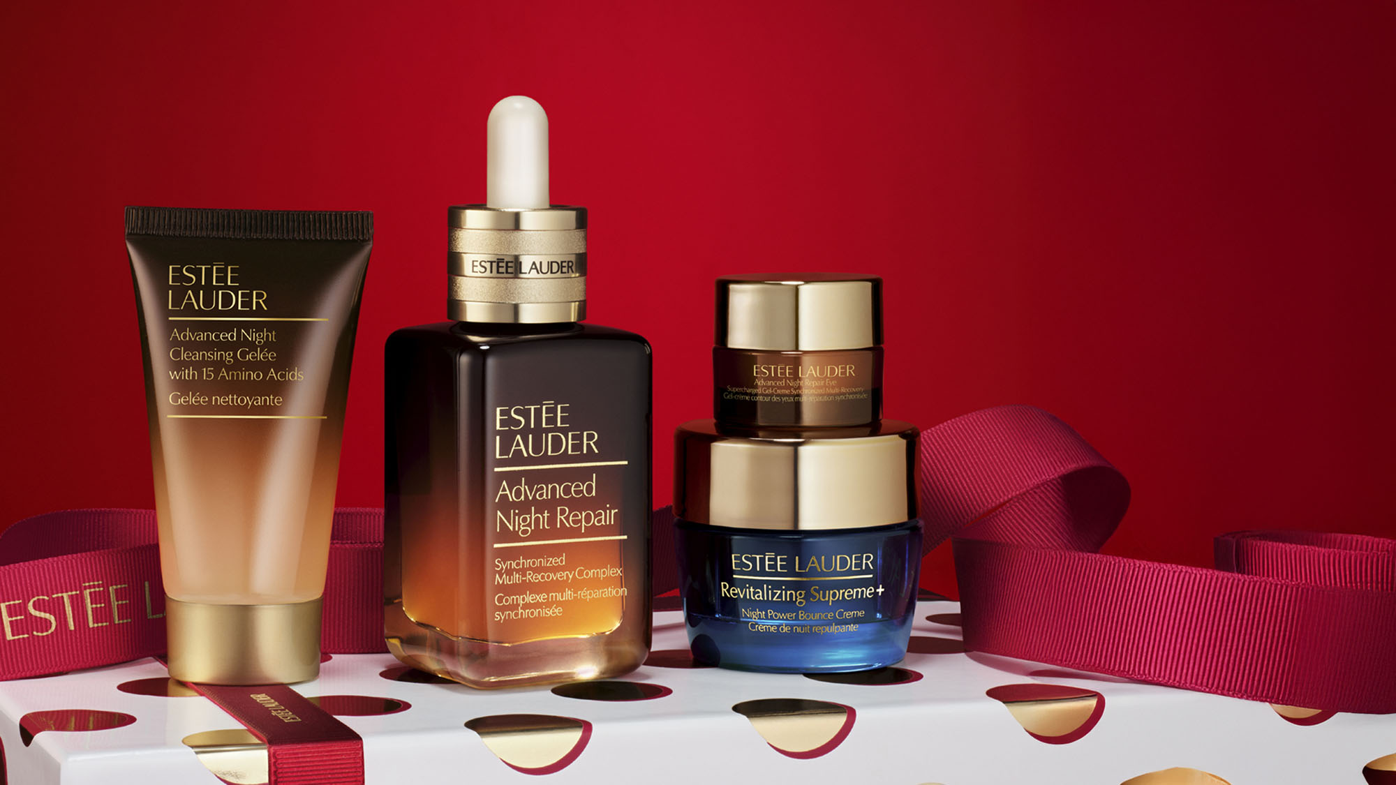Estee Lauder beauty products displayed against a red background with a ribbon; includes a discount offer at the top.
