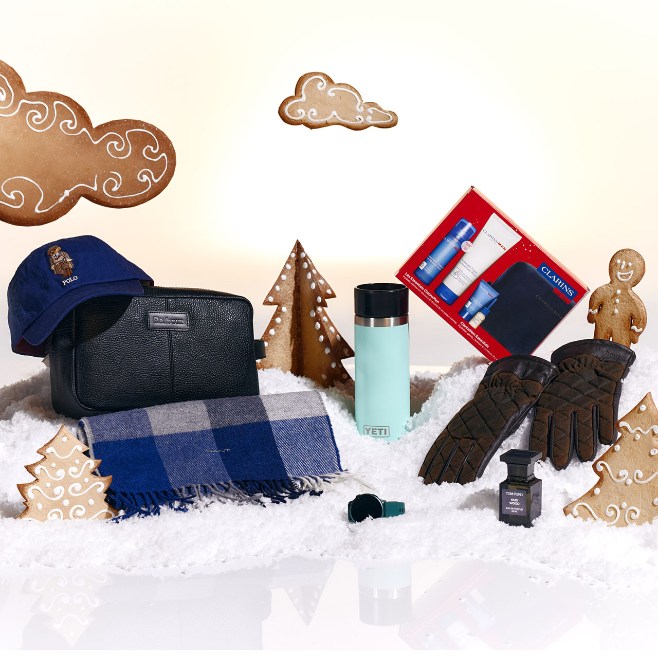 Winter-themed items including gloves, a hat, scarf, tumbler, grooming kit, and gingerbread decorations on snow-like surface.