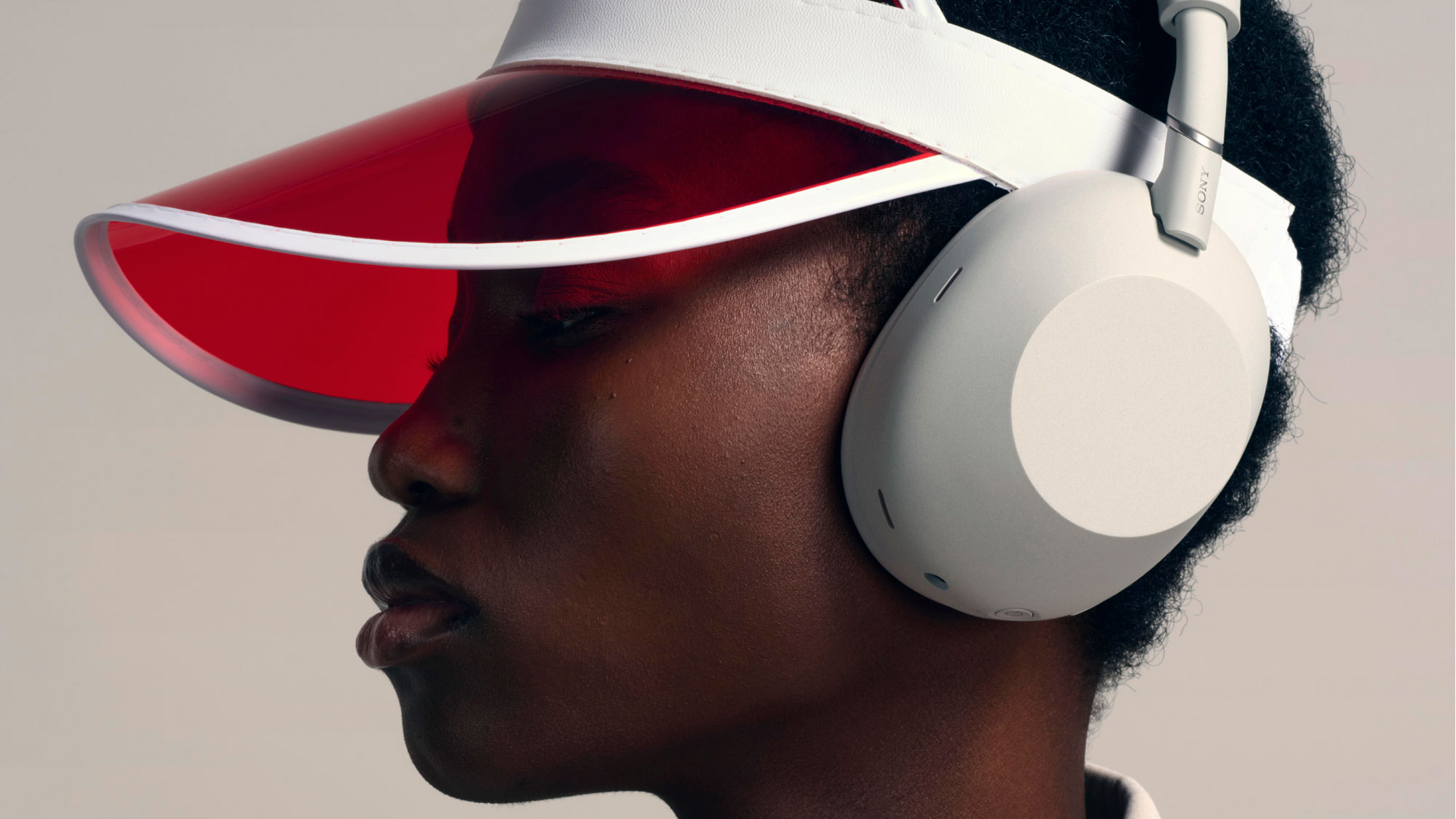 A woman wears headphones and a red sun visor.