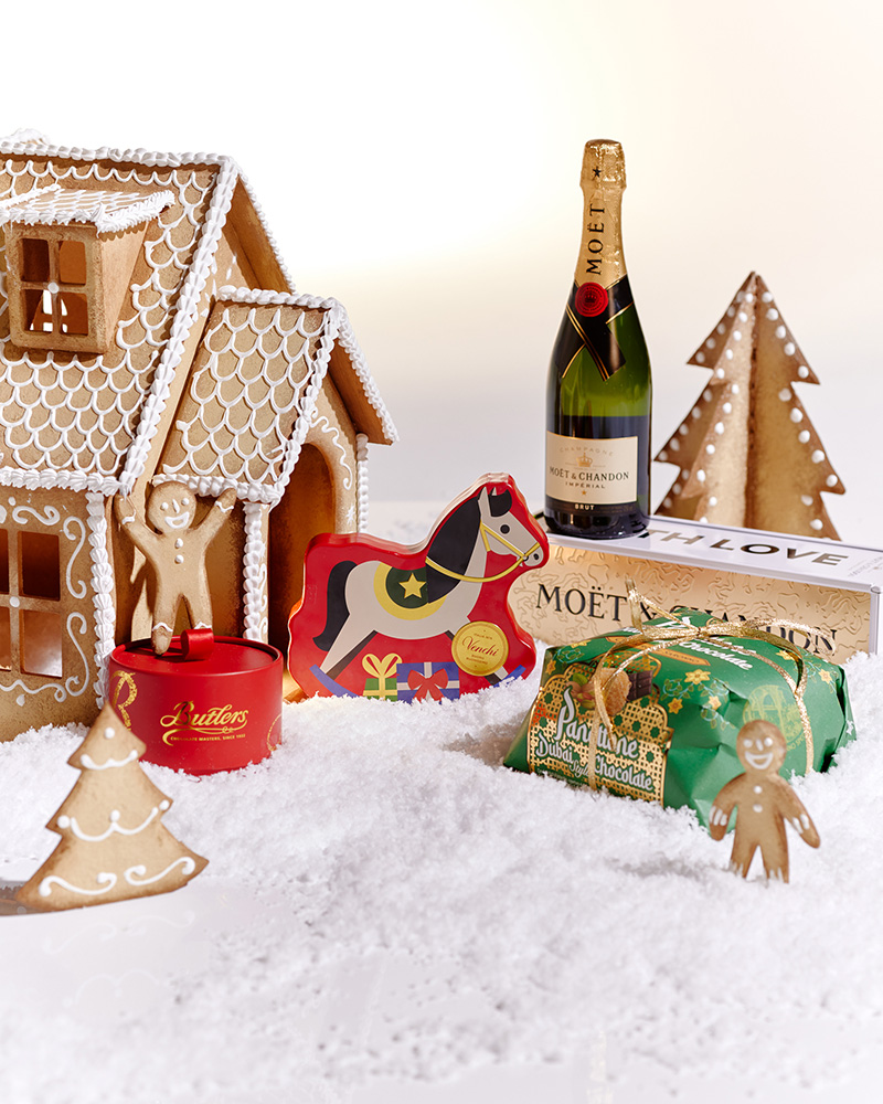 Festive hamper with a basket, floral arrangement, Christmas-themed foods, and decorative products on display.