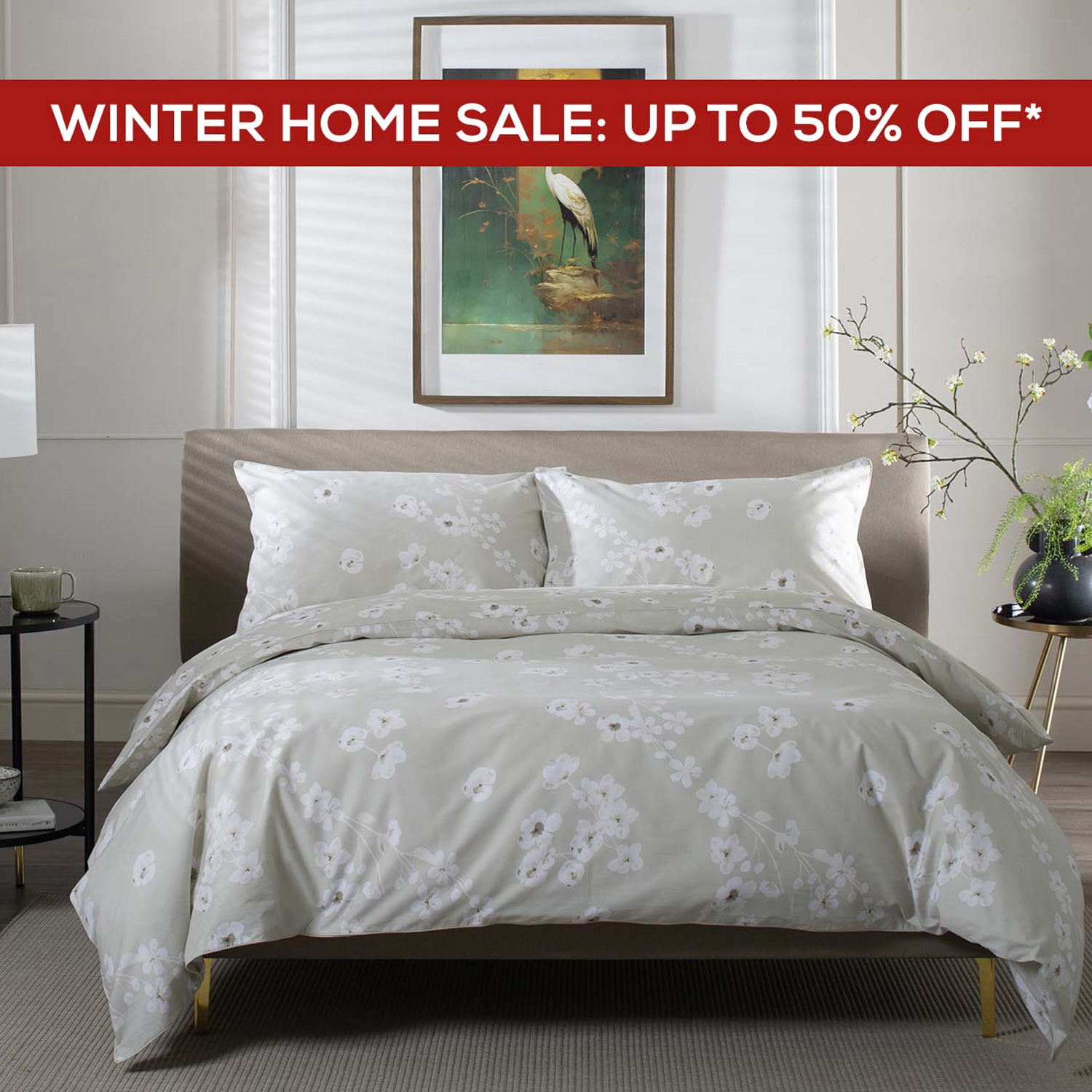 A stylish bedroom with a patterned duvet, a bedside table with a lamp, a potted plant, and a framed bird painting on the wall.