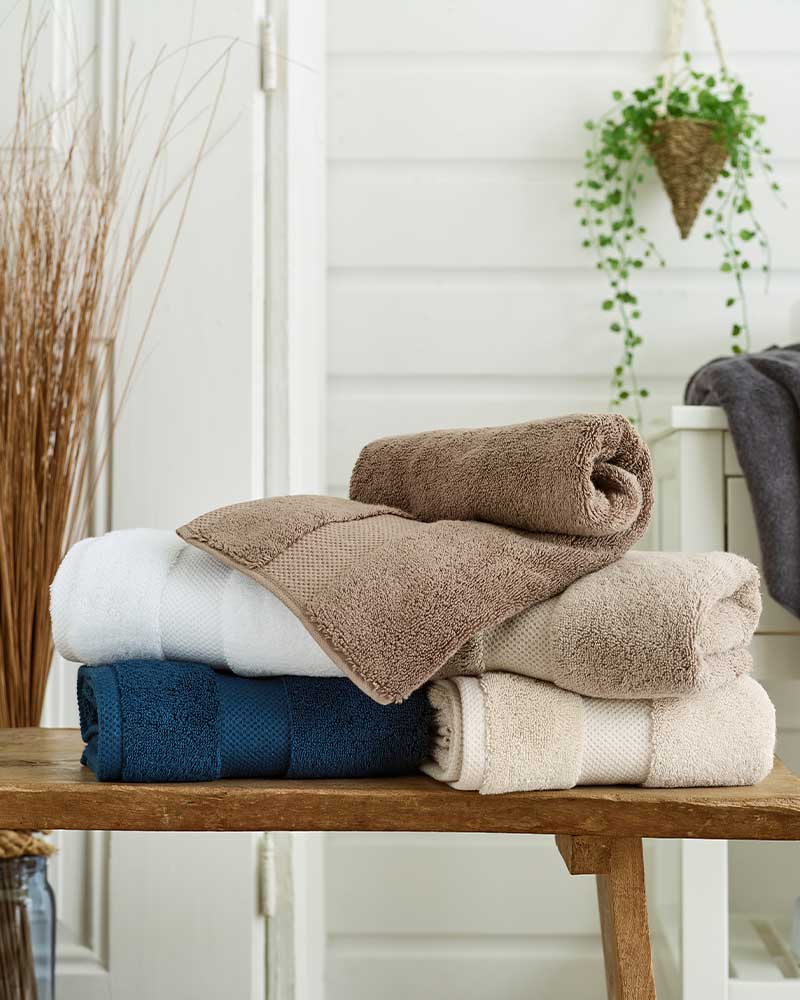 A white candle and a clear vase of white flowers on a glass table.