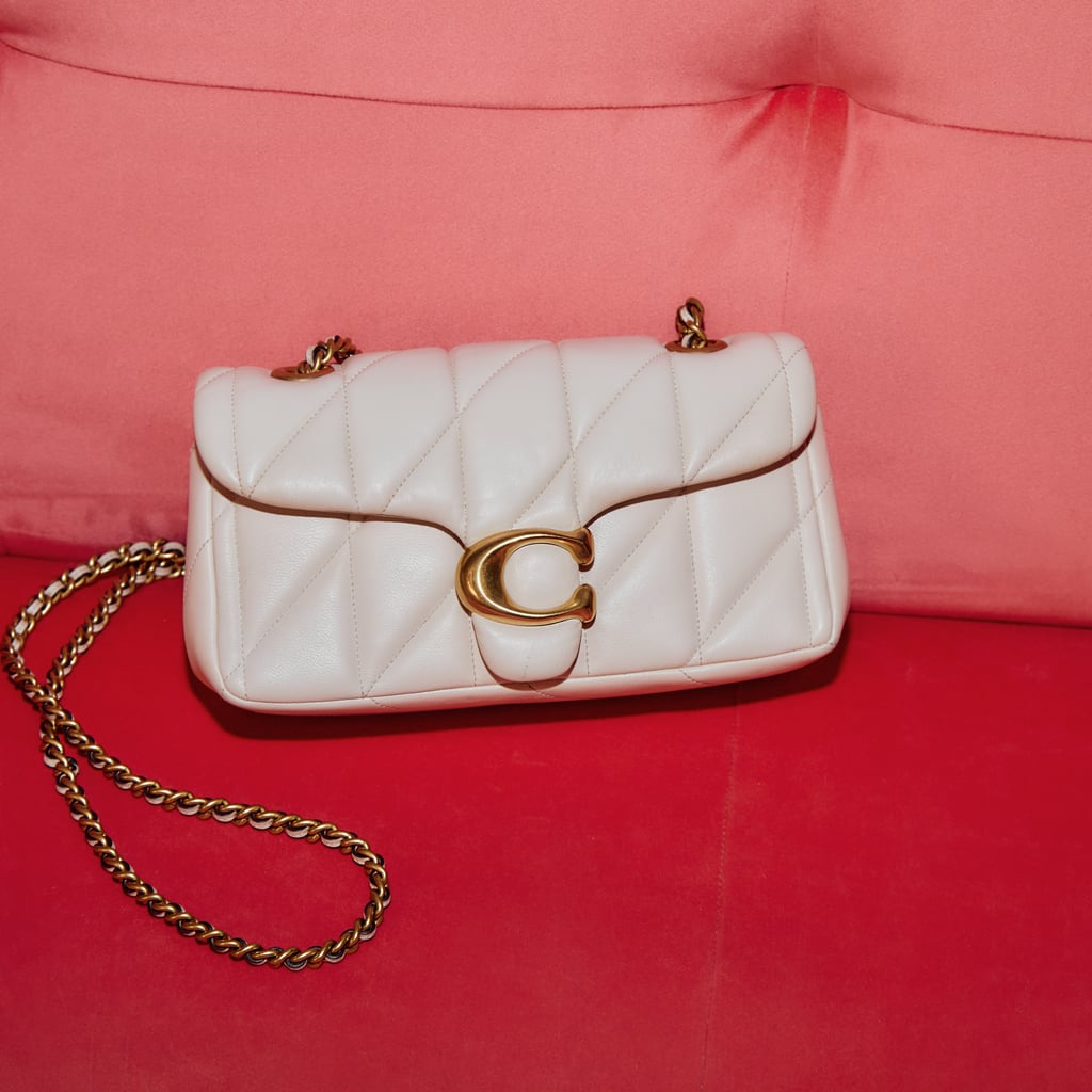 A white quilted handbag with a gold chain and clasp, resting on a red and pink cushioned surface.