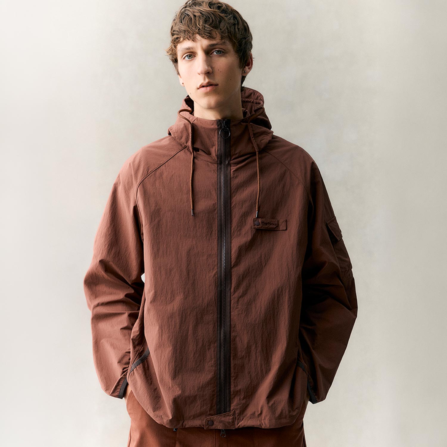 Man wearing rust-brown hooded jacket with full zip fastening and drawstring details
