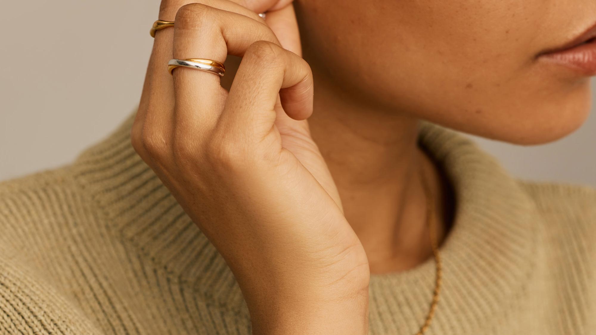 Close-up of woman's hand wearing layered gold and silver rings