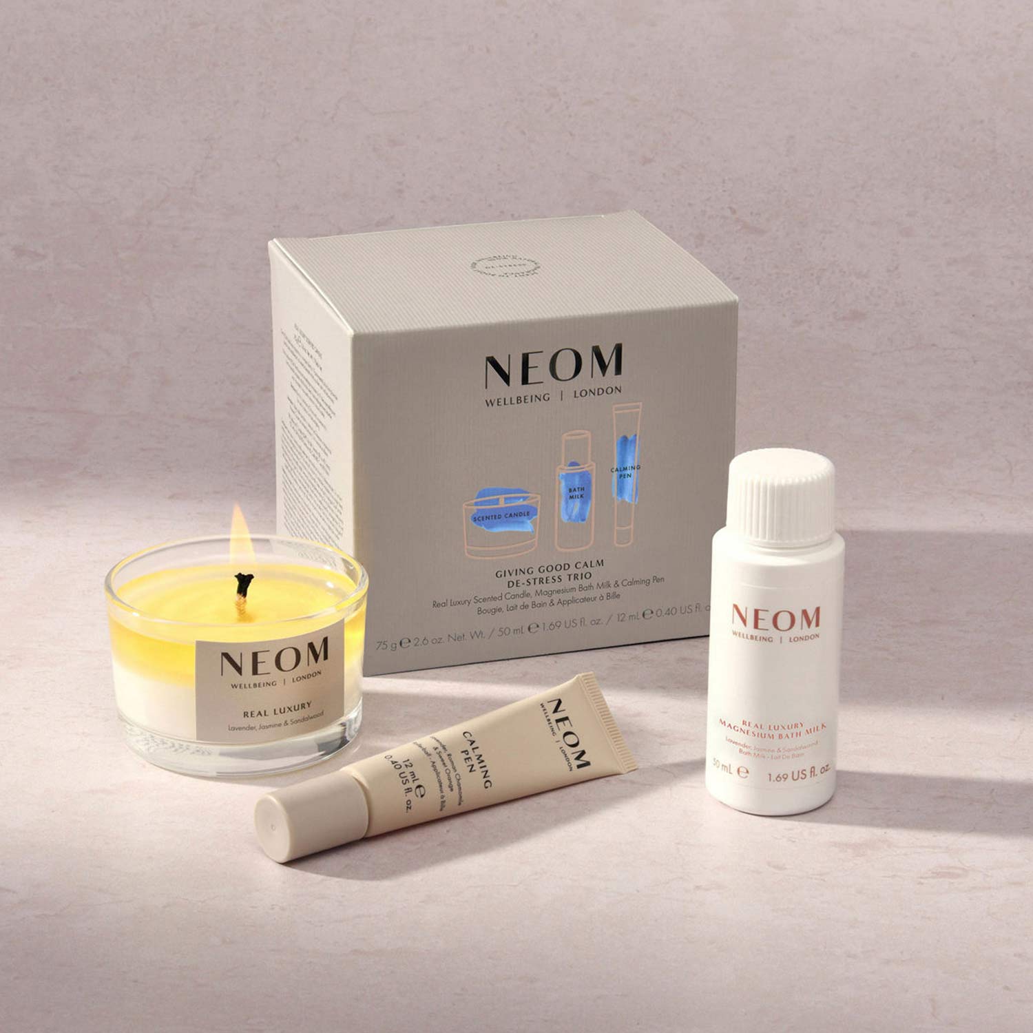 Neom Wellbeing products: a candle, a tube, a bottle, and a box, arranged on a light surface.