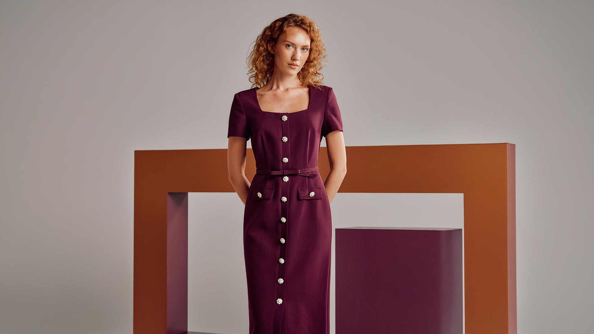 Woman wearing burgundy button-front midi dress with short sleeves against neutral background