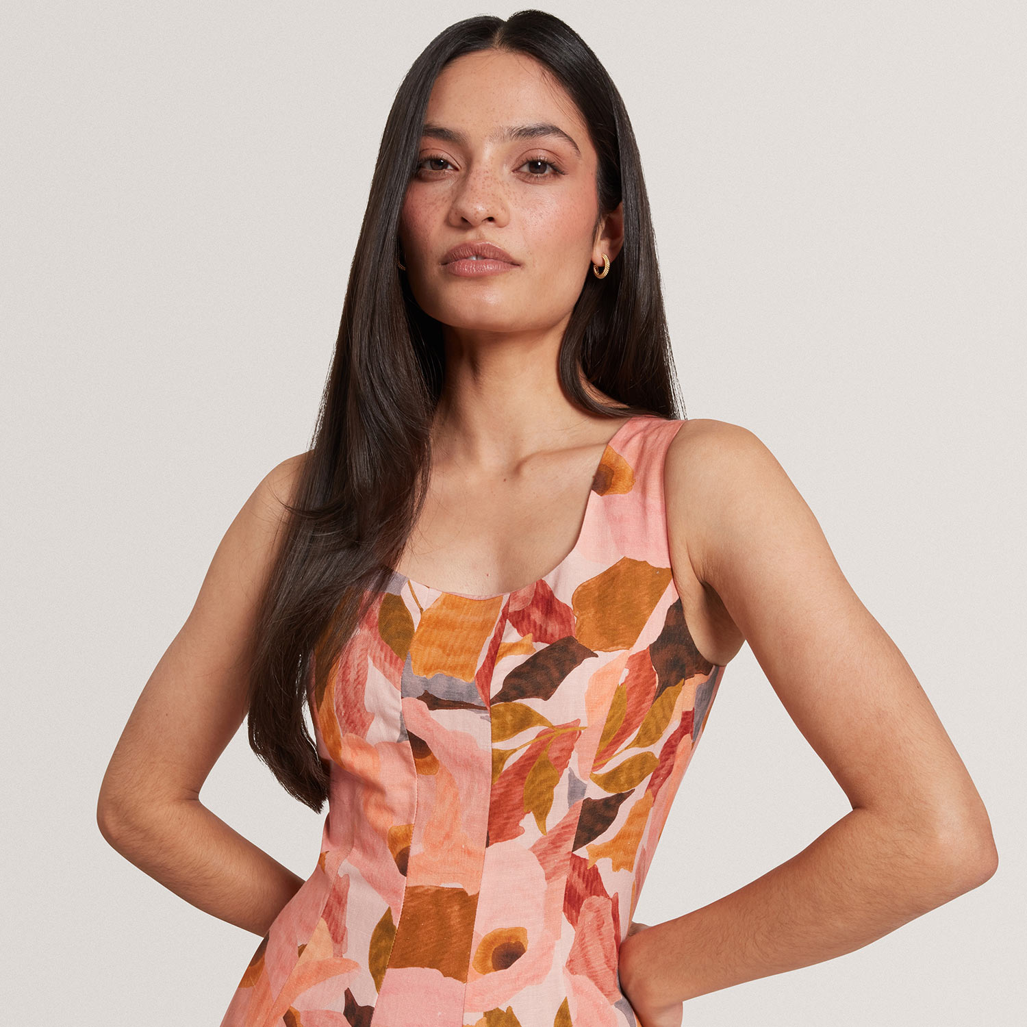 Woman wearing coral and orange floral dress with sleeveless cut