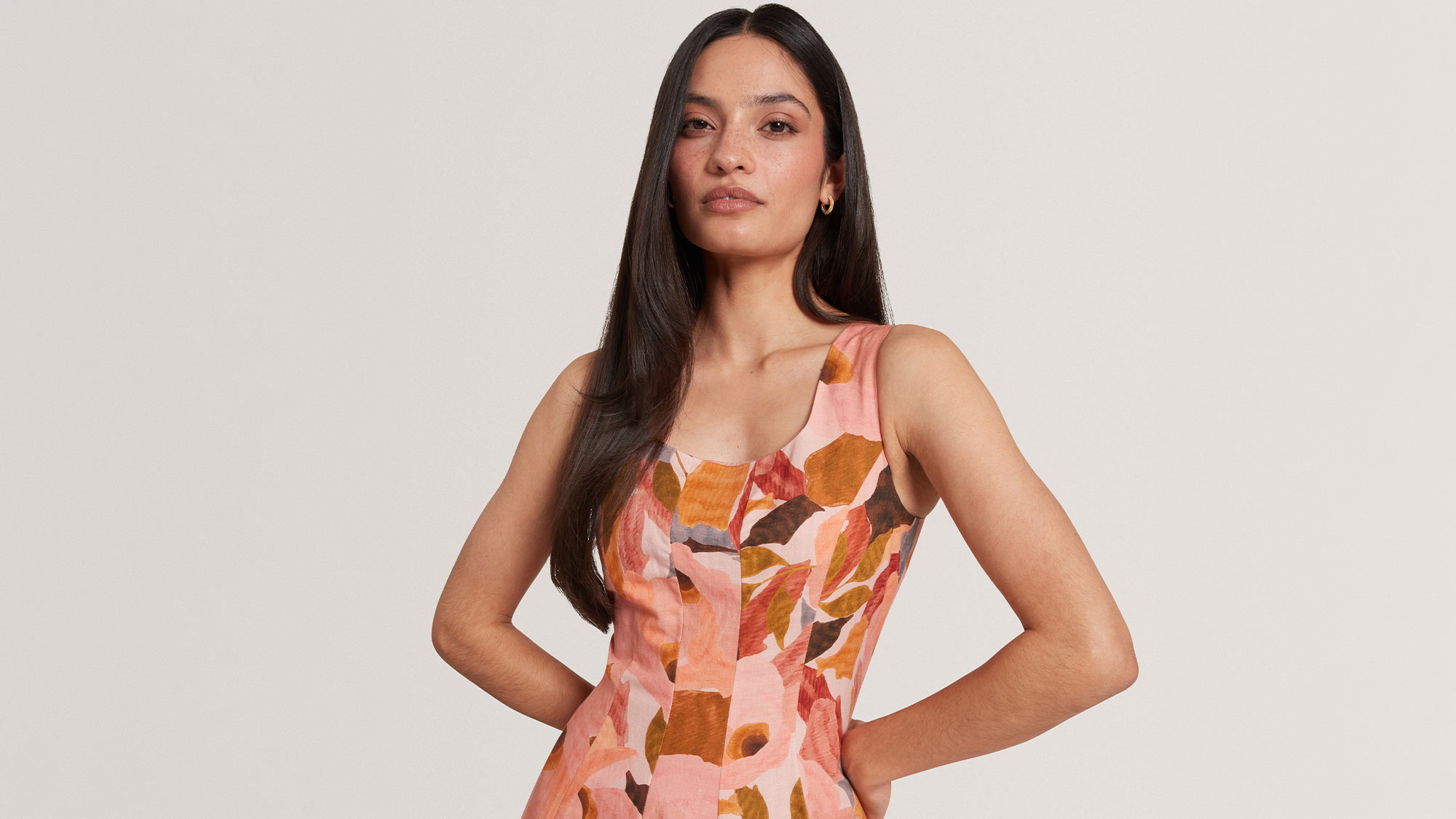 Woman wearing coral and orange floral dress with sleeveless cut