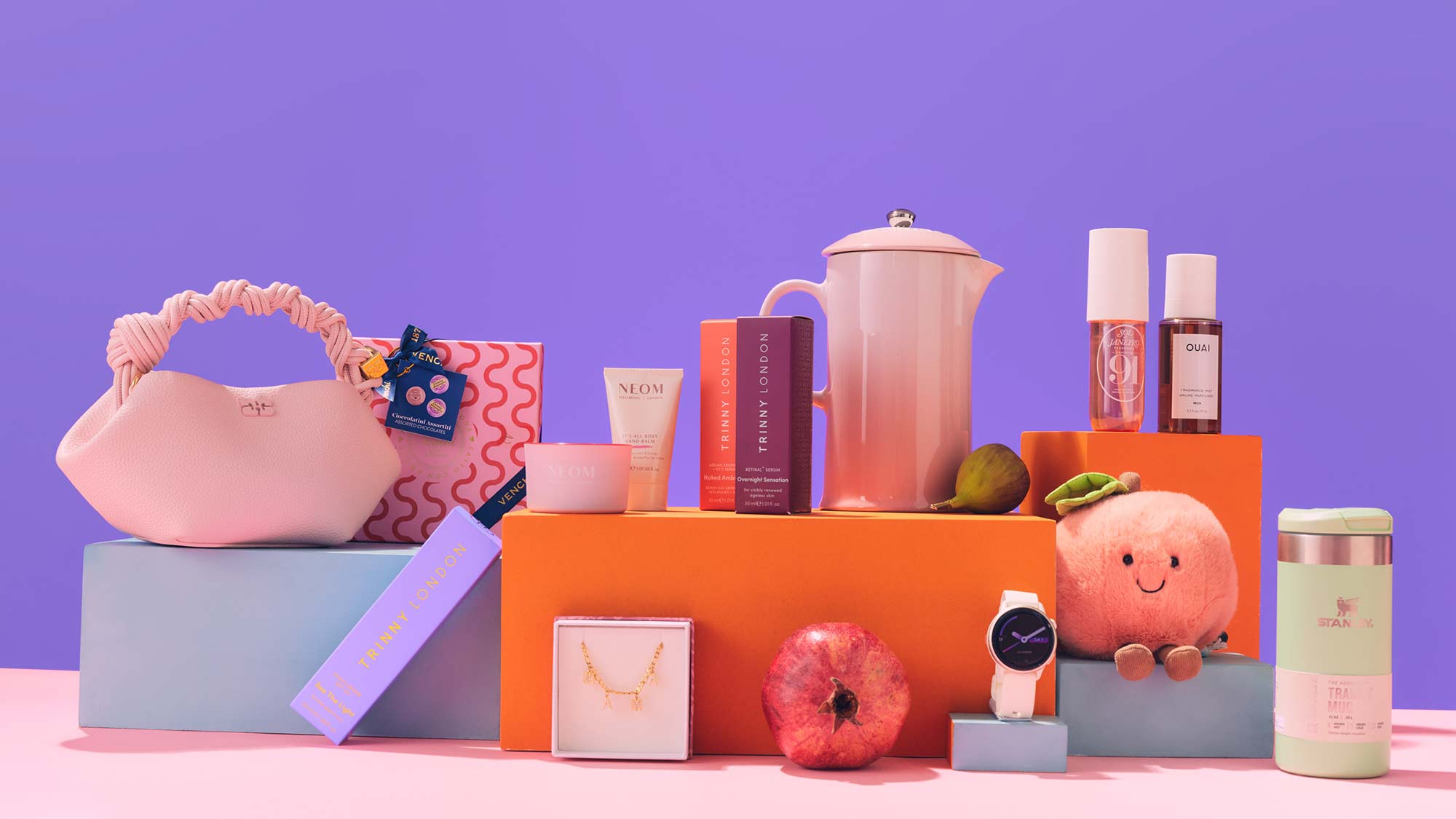 A colorful arrangement of assorted items, including a handbag, watch, cosmetics, and plush toy, displayed against a purple background.