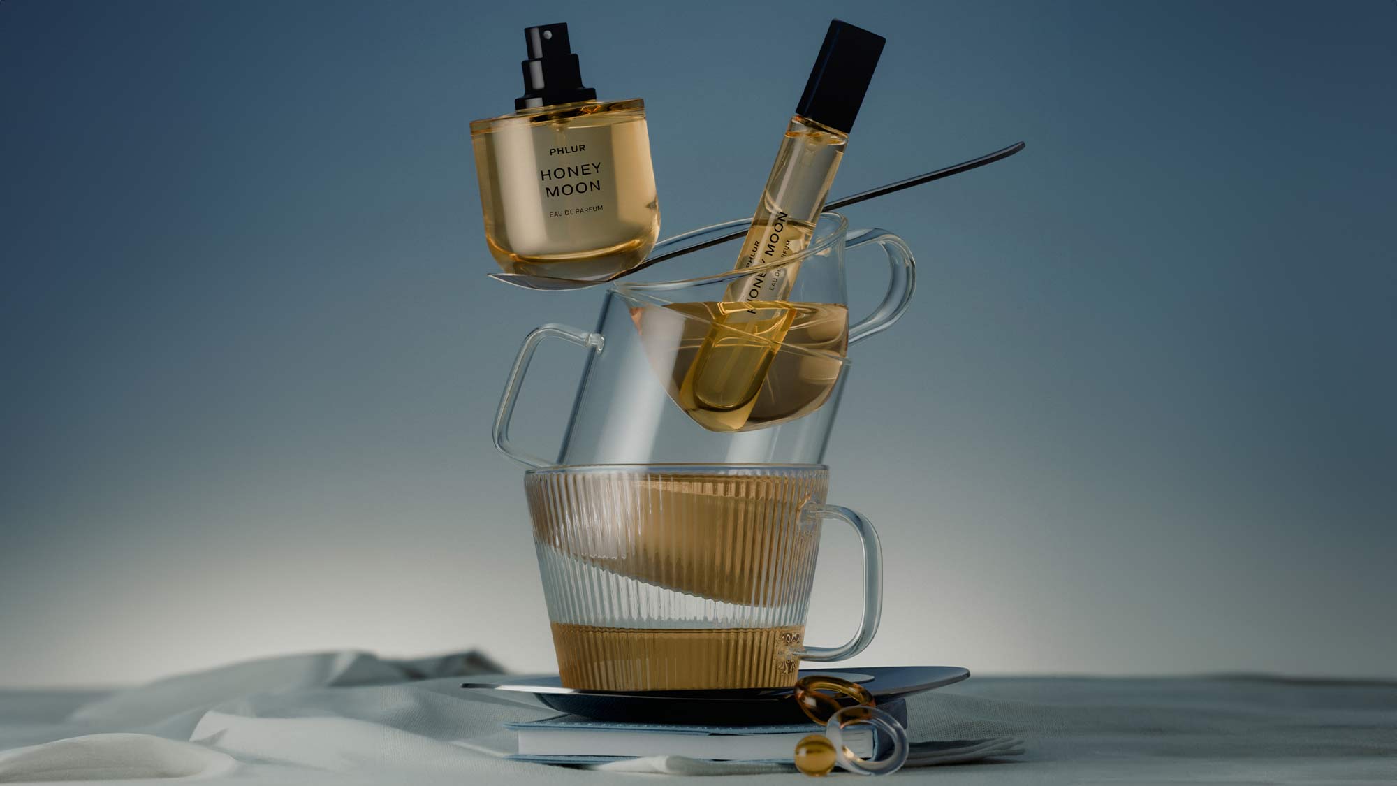 Perfume bottles labeled 'Honey Moon' artfully arranged on stacked glass cups with a moody background.