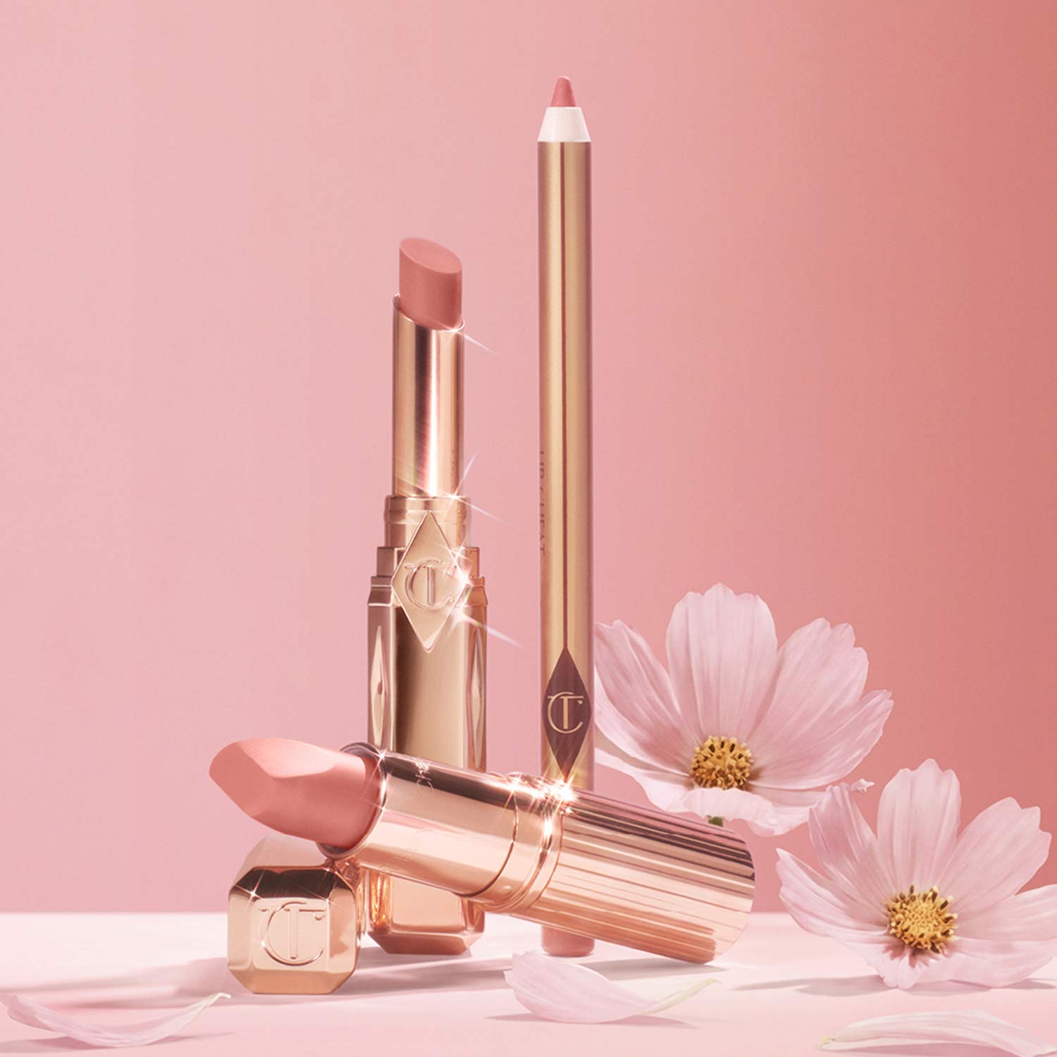 Lipstick and lip liner set with pink flowers on a soft pink background.