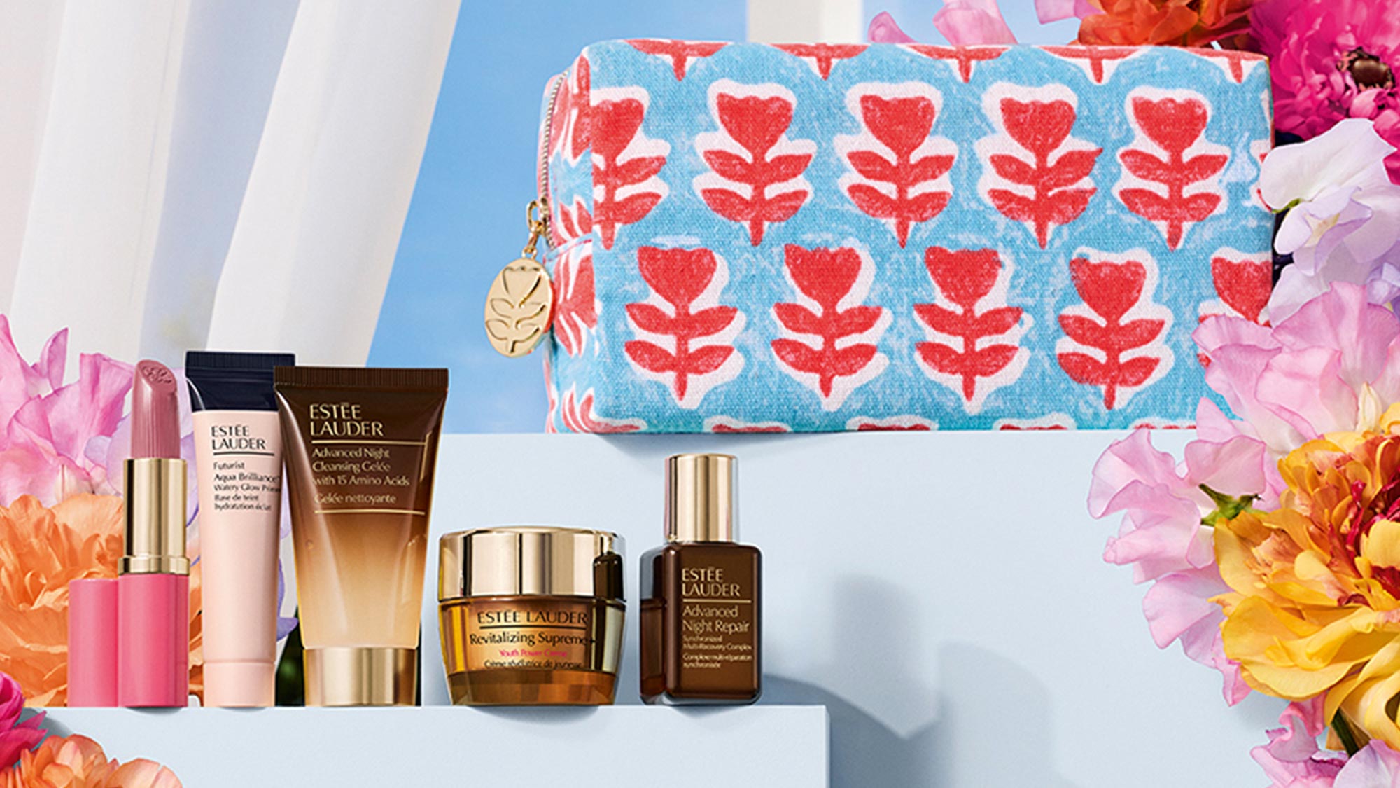 Estée Lauder skincare products displayed with a blue patterned cosmetics pouch and colourful flowers