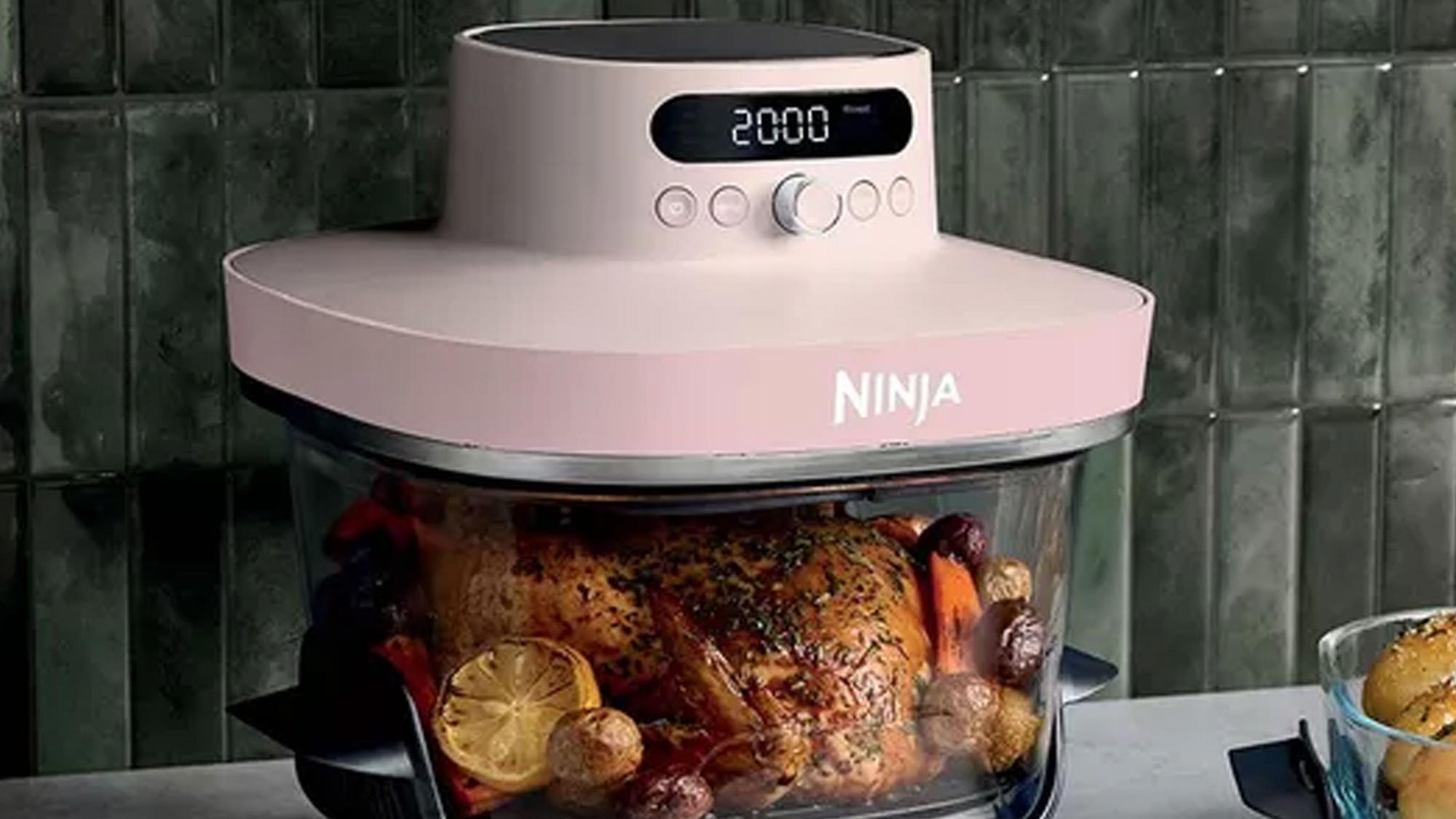 Pink Ninja Crispi Pro air fryer with digital display showing 200°C, filled with roasted vegetables and lemon slices