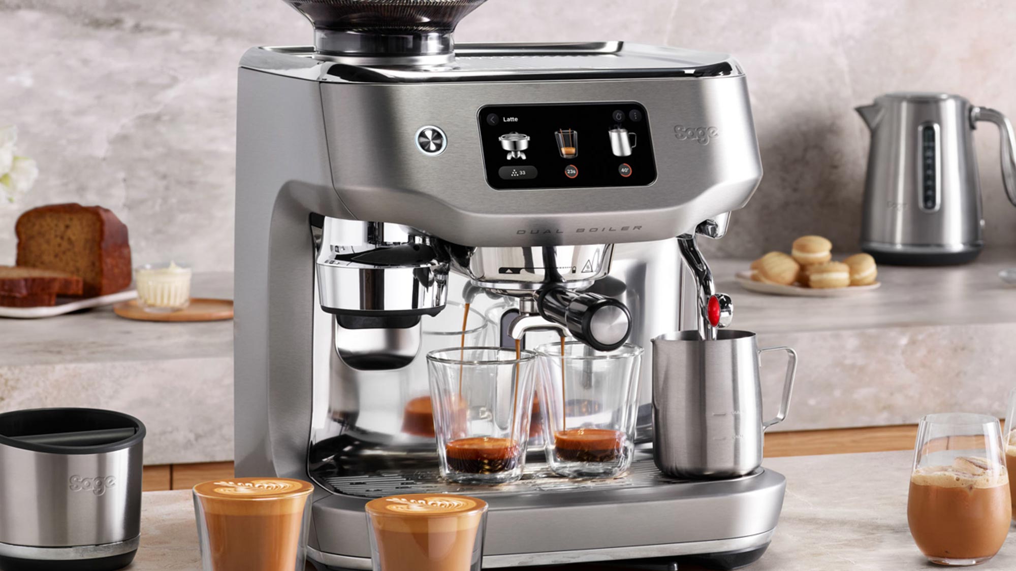 Sage dual boiler espresso machine in stainless steel with digital display, pouring espresso into glasses with latte art