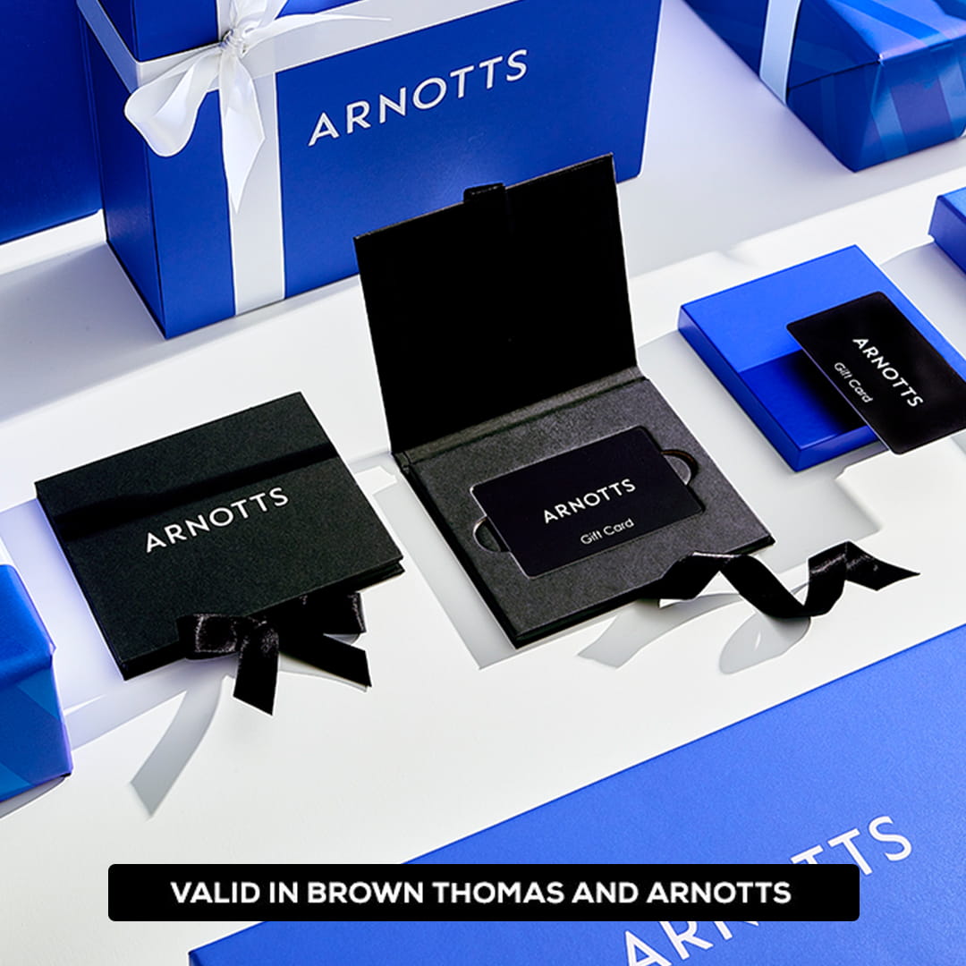 Gift cards in black holders with ribbons, placed beside blue Arnotts gift boxes tied with white ribbons. Text on the image states, 'Valid in Brown Thomas and Arnotts.'