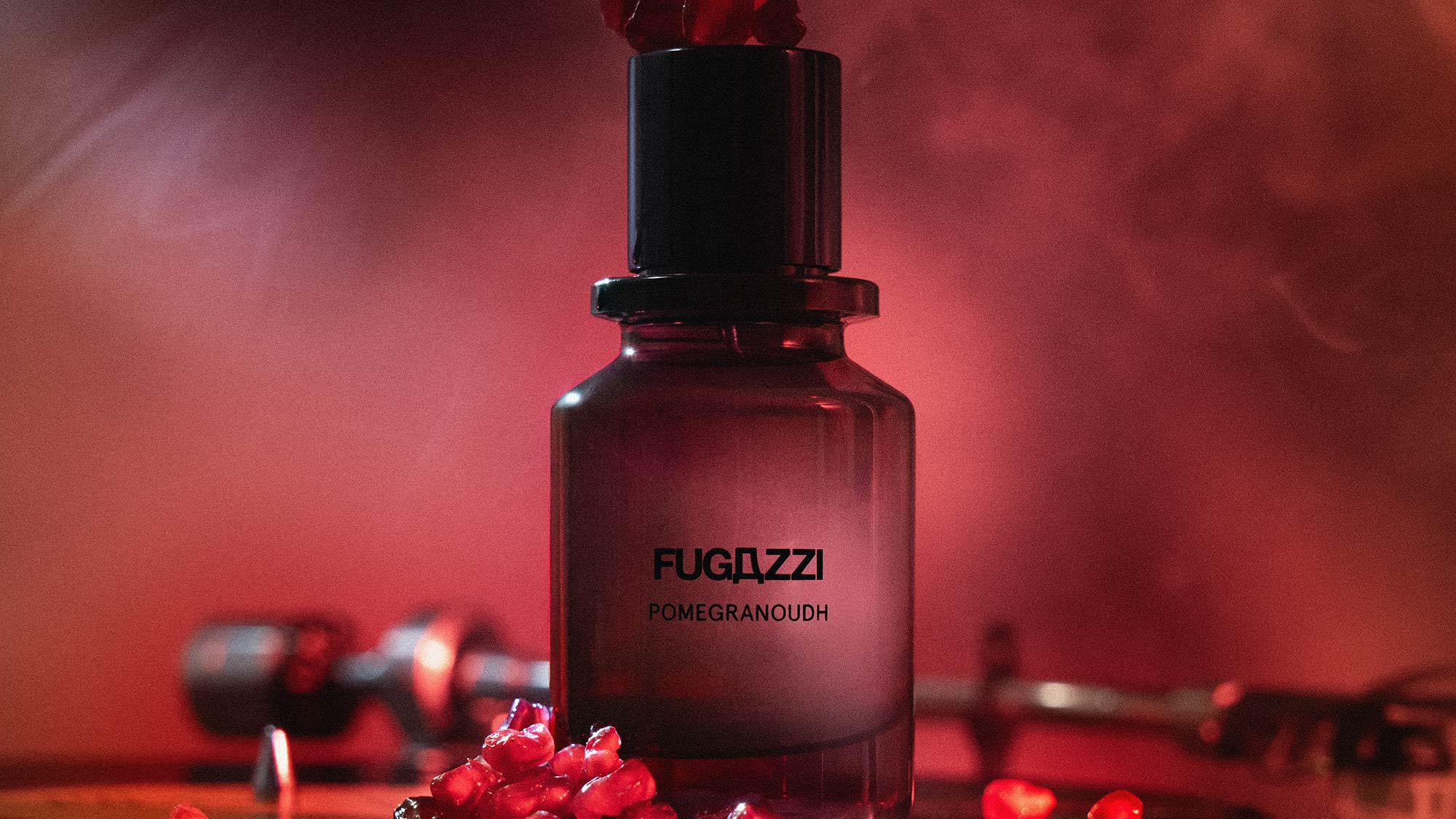 Fugazzi Pomegranoudh Extrait de Parfum bottle with red pomegranate seeds on deep red background