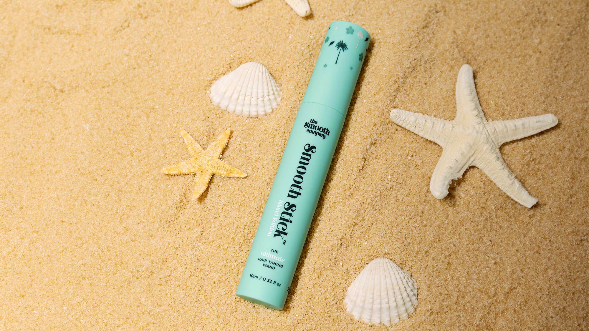 The Smooth Company limited edition Island Stick hair product on sand with starfish and seashells.