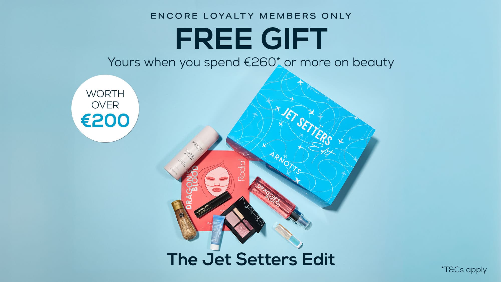 A promotional image for Arnotts' 'The Jet Setters Edit' beauty box. It offers a free gift worth over €200 for Encore loyalty members spending €260 or more on beauty products. The box includes various cosmetics, such as blush, lipstick, mascara, and skincare items, all arranged around a blue box labelled 'Jet Setters.' Terms and conditions apply.