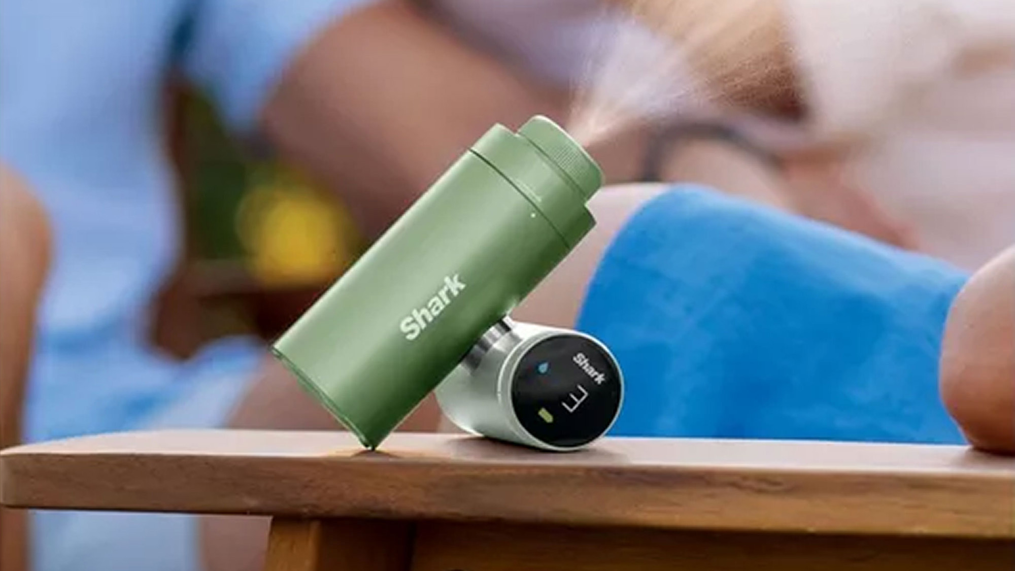 Shark portable fan in sage green with digital display held in hand outdoors