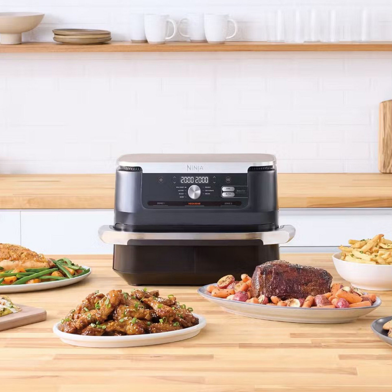 Ninja air fryer on kitchen counter with cooked meals including steak, chicken, chips, and roasted vegetables