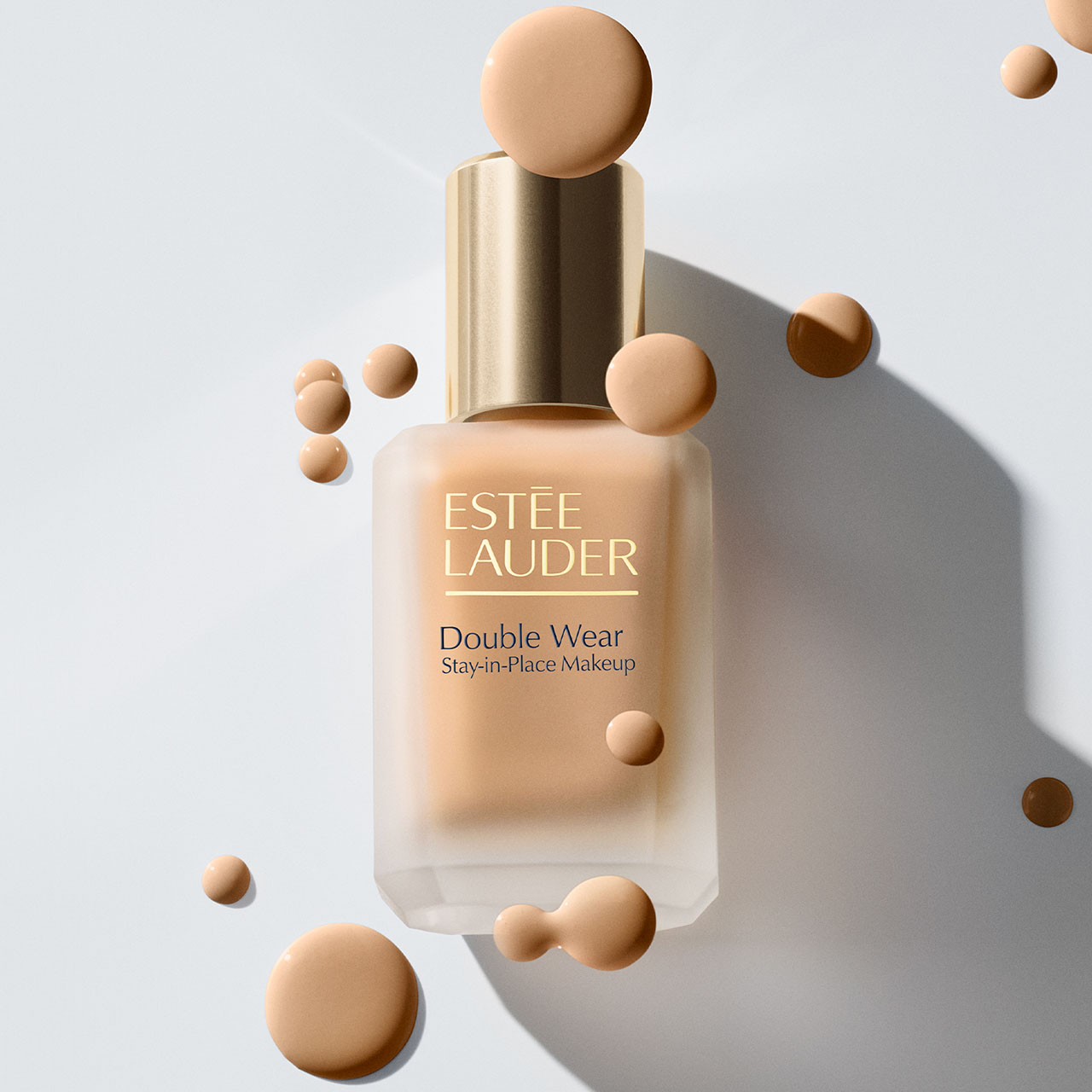 Estée Lauder Double Wear Stay-in-Place Makeup foundation bottle with gold cap and decorative beige spheres