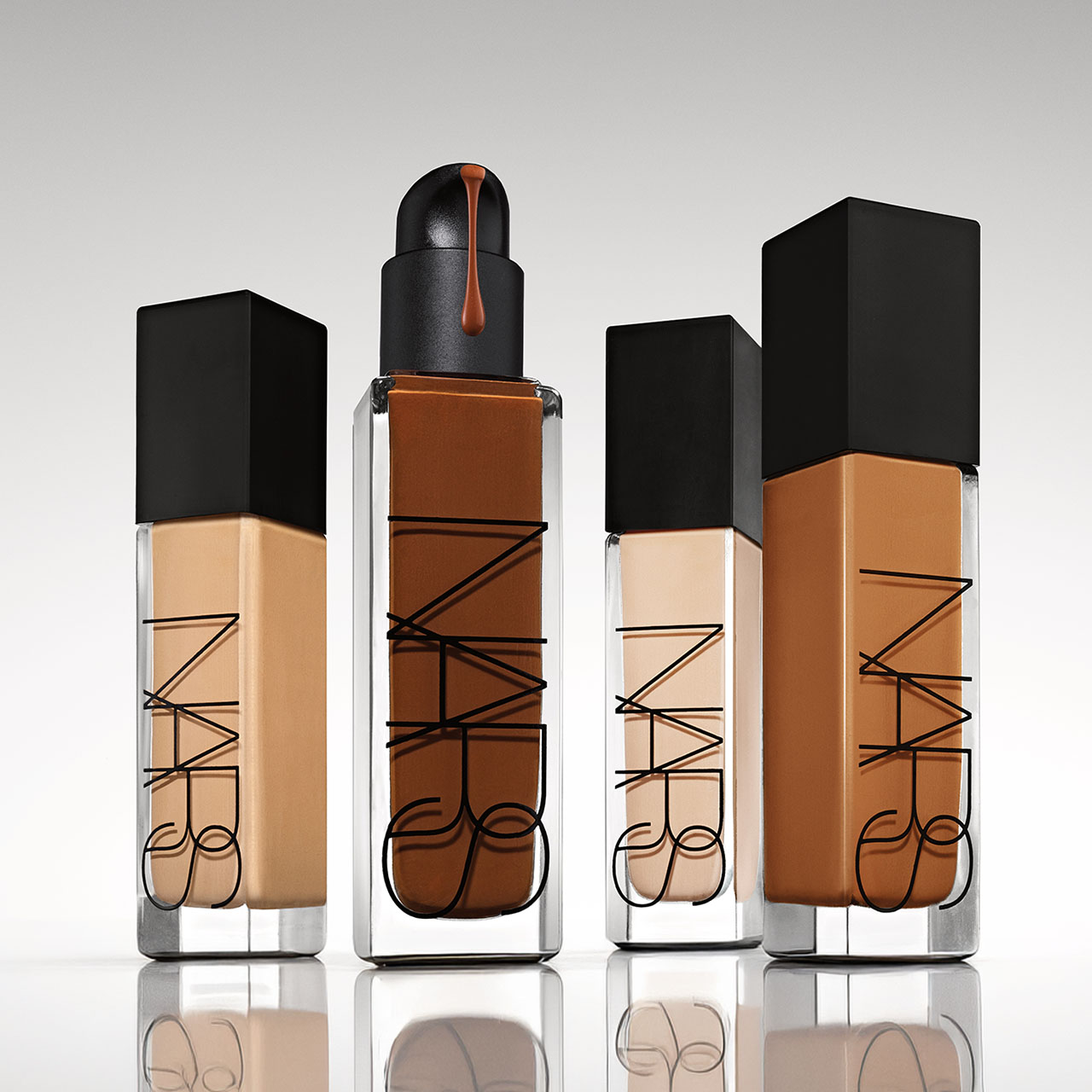 Four bottles of NARS Natural Radiant Longwear Foundation in varying shades with black caps