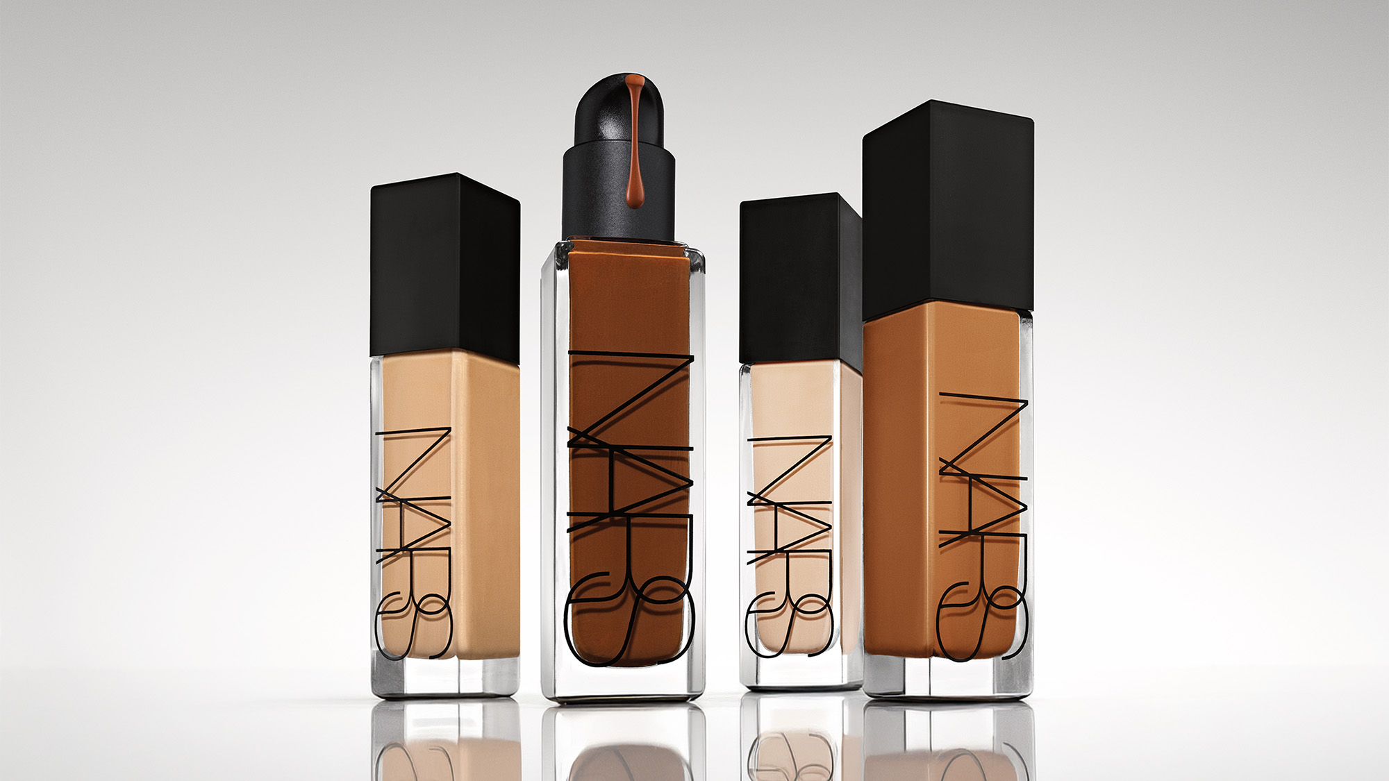 Four bottles of NARS Natural Radiant Longwear Foundation in varying shades with black caps