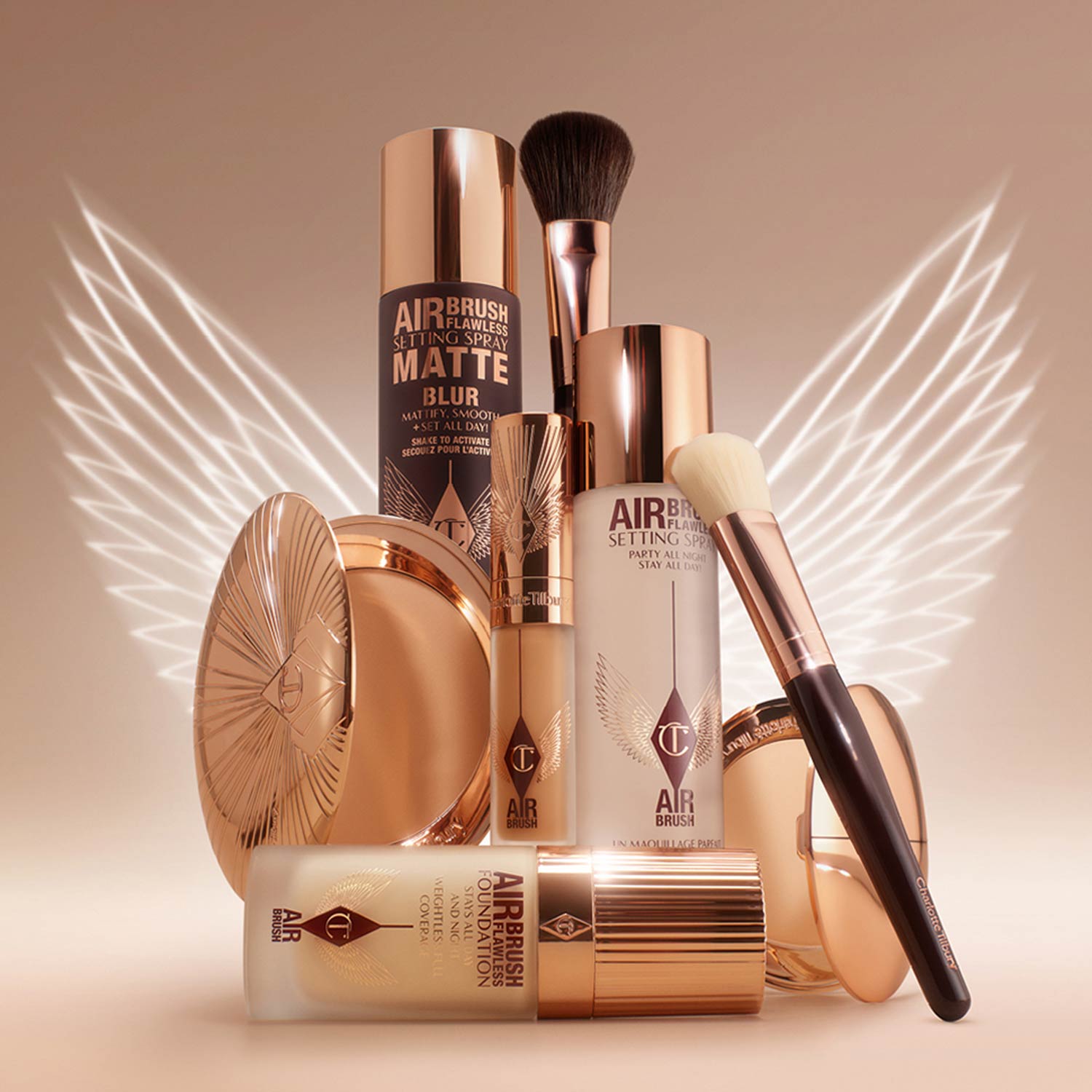 Collection of complexion makeup products including powder, setting sprays, foundation, and brushes with rose gold packaging
