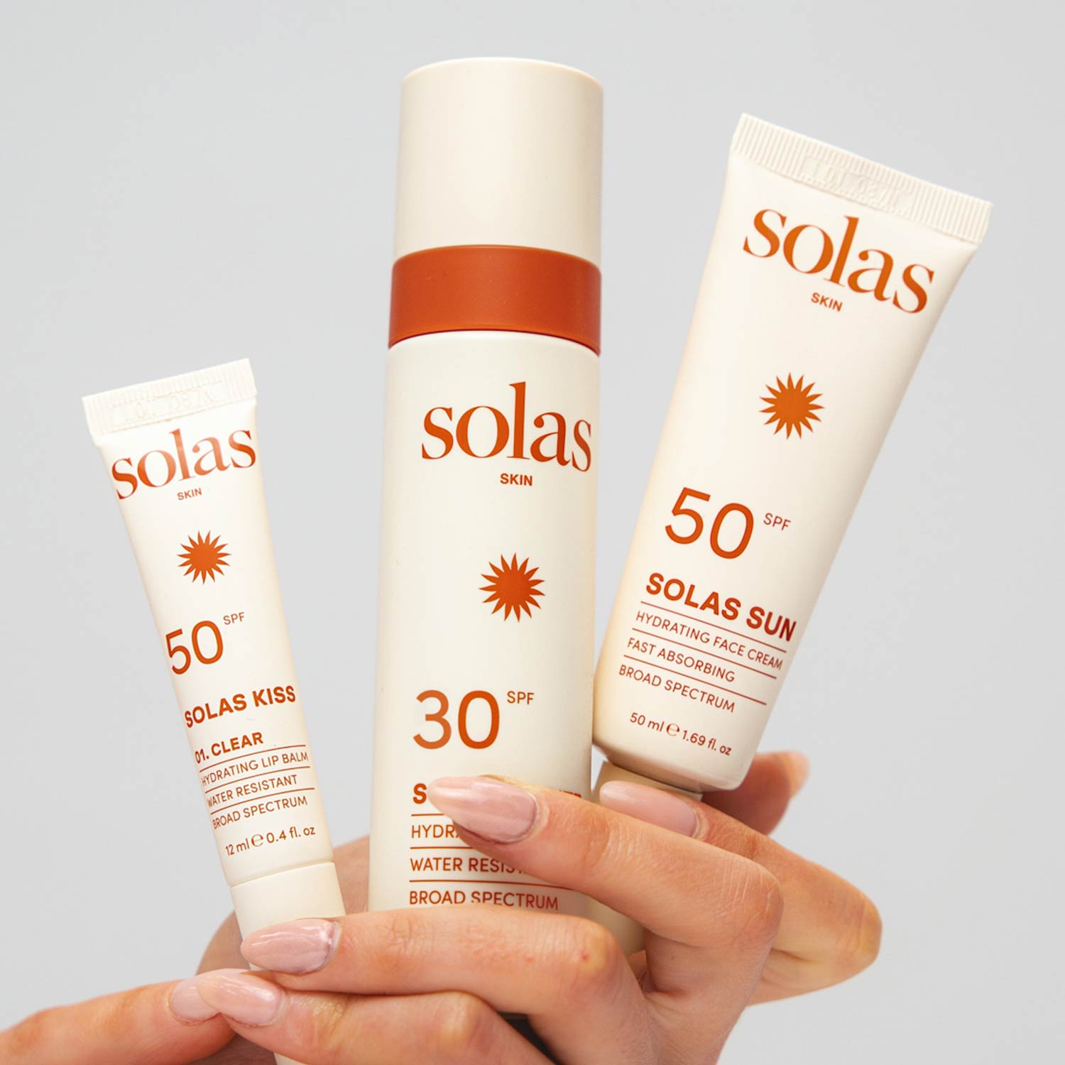 Three Solas Skin sunscreen products with SPF 50 and SPF 30 held in hand against neutral background