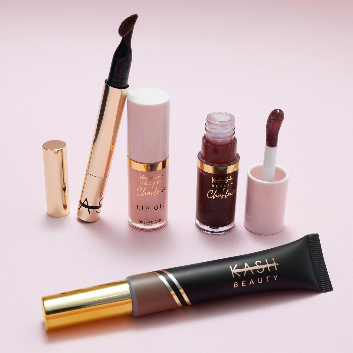 Kash Beauty cosmetics including lipstick, lip oil, liquid eyeshadow and foundation displayed on pale pink background