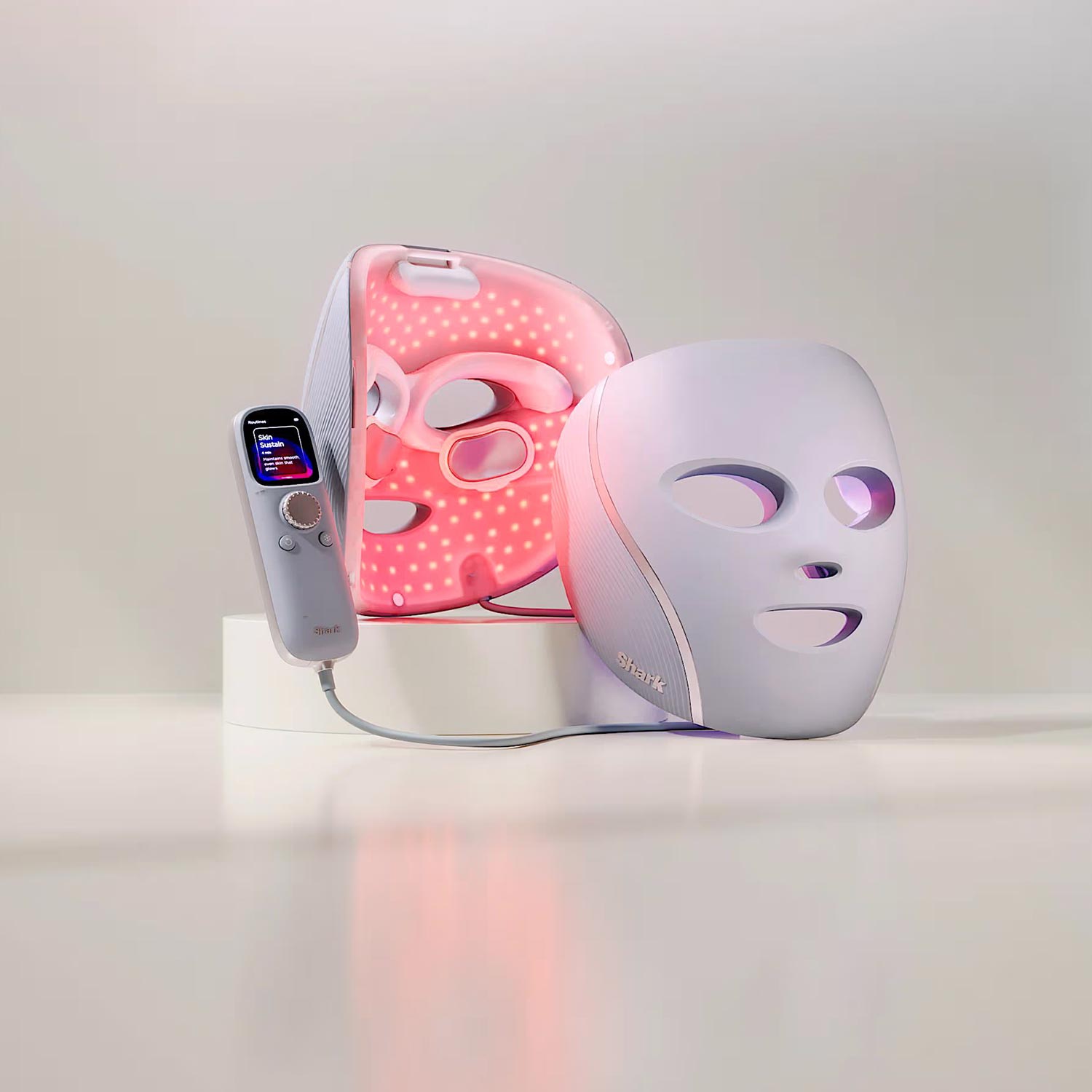 LED light therapy face mask and handheld red light therapy device with digital display on white surface.