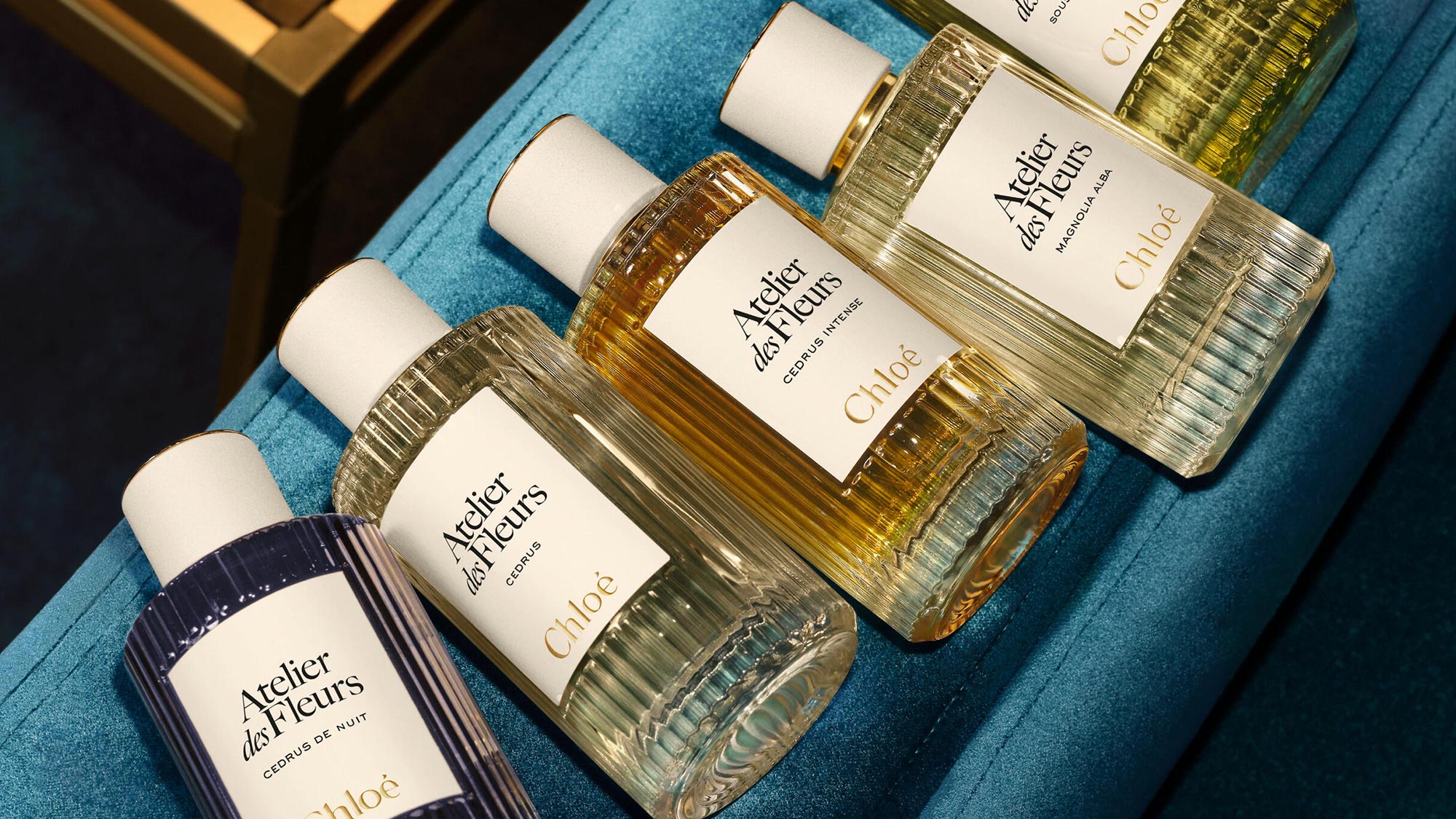 Collection of Chloé Atelier des Fleurs fragrance bottles with white and gold labels on turquoise surface