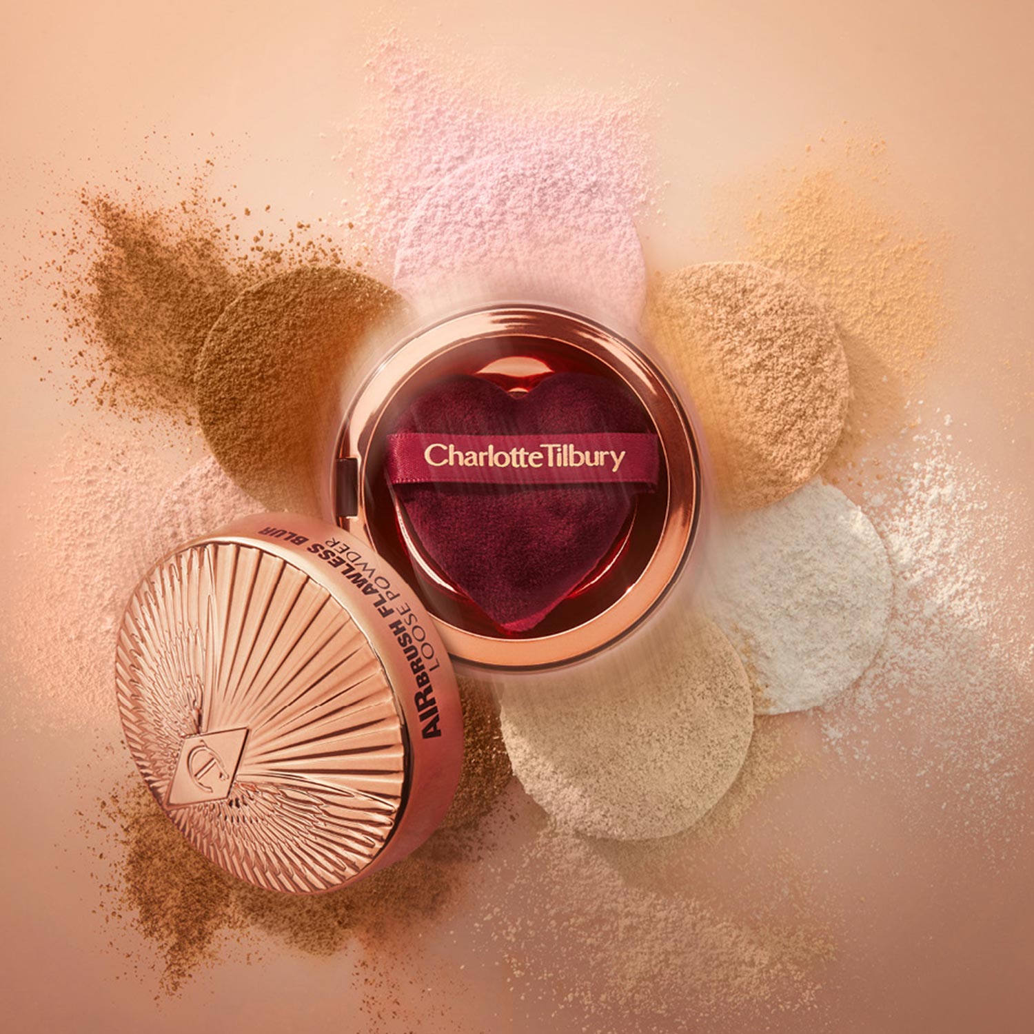 Charlotte Tilbury makeup products displayed with loose powder pigments in bronze, pink, and gold tones