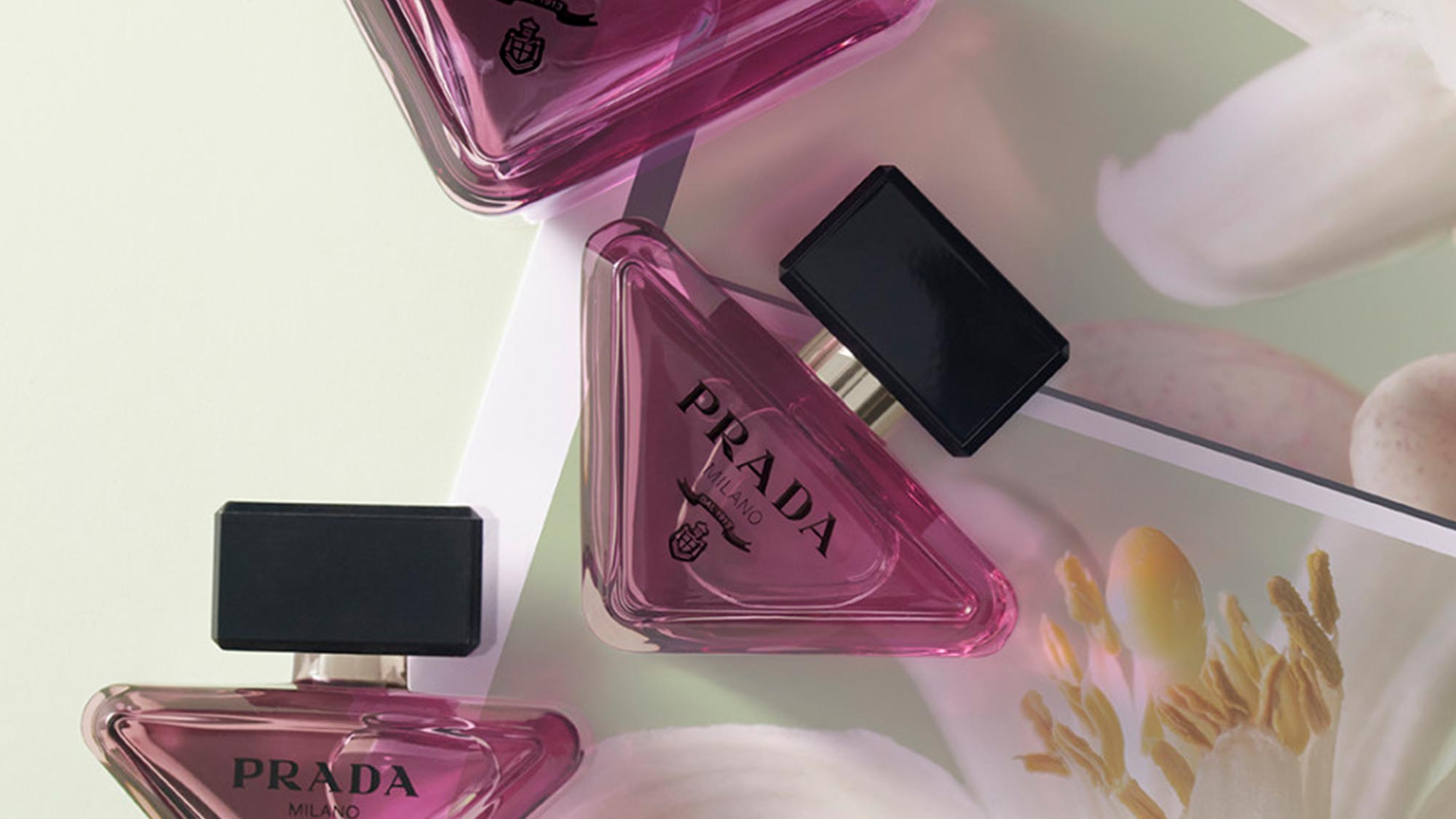Prada Milano fragrance bottles in magenta pink with black atomiser caps on soft pastel background