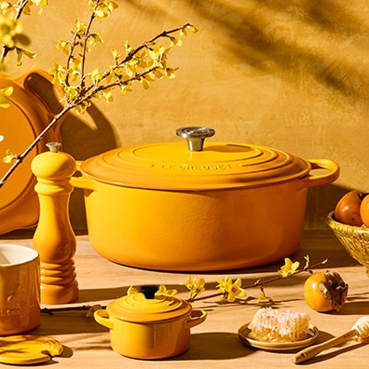 Yellow Le Creuset cast iron cookware arranged with decorative yellow kitchen accessories