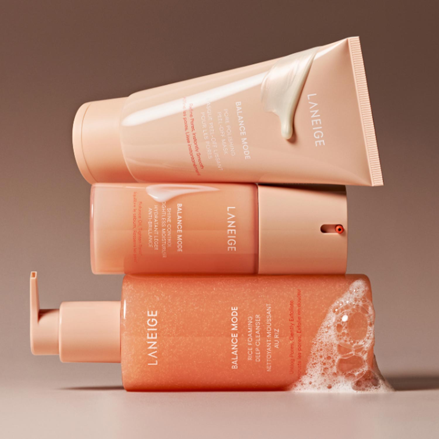 Three Laneige Balance Mode skincare products in coral and cream packaging with textured powder display