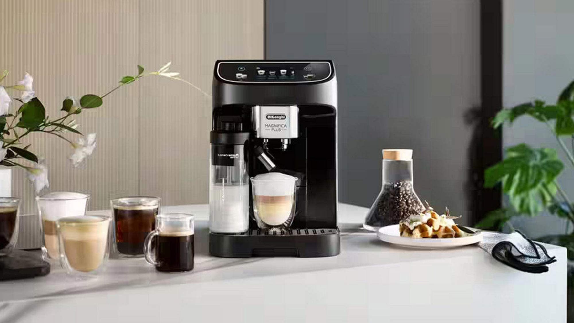 Delonghi coffee machine surrounded by cups of coffee, coffee beans, and fresh flowers on white table