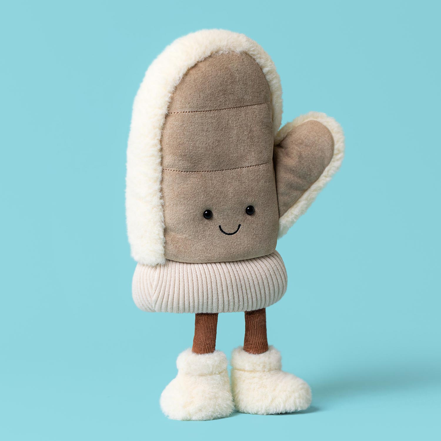 Plush toy mitten character with smiling face, beige fabric with cream fleece trim and brown legs against blue background