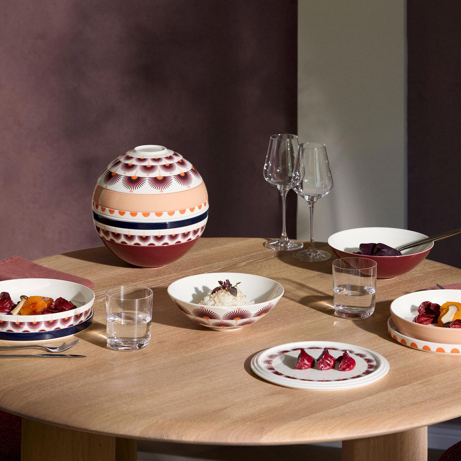 Dining table set with patterned bowls, plates, wine glasses and decorative sphere inspired by Japanese design